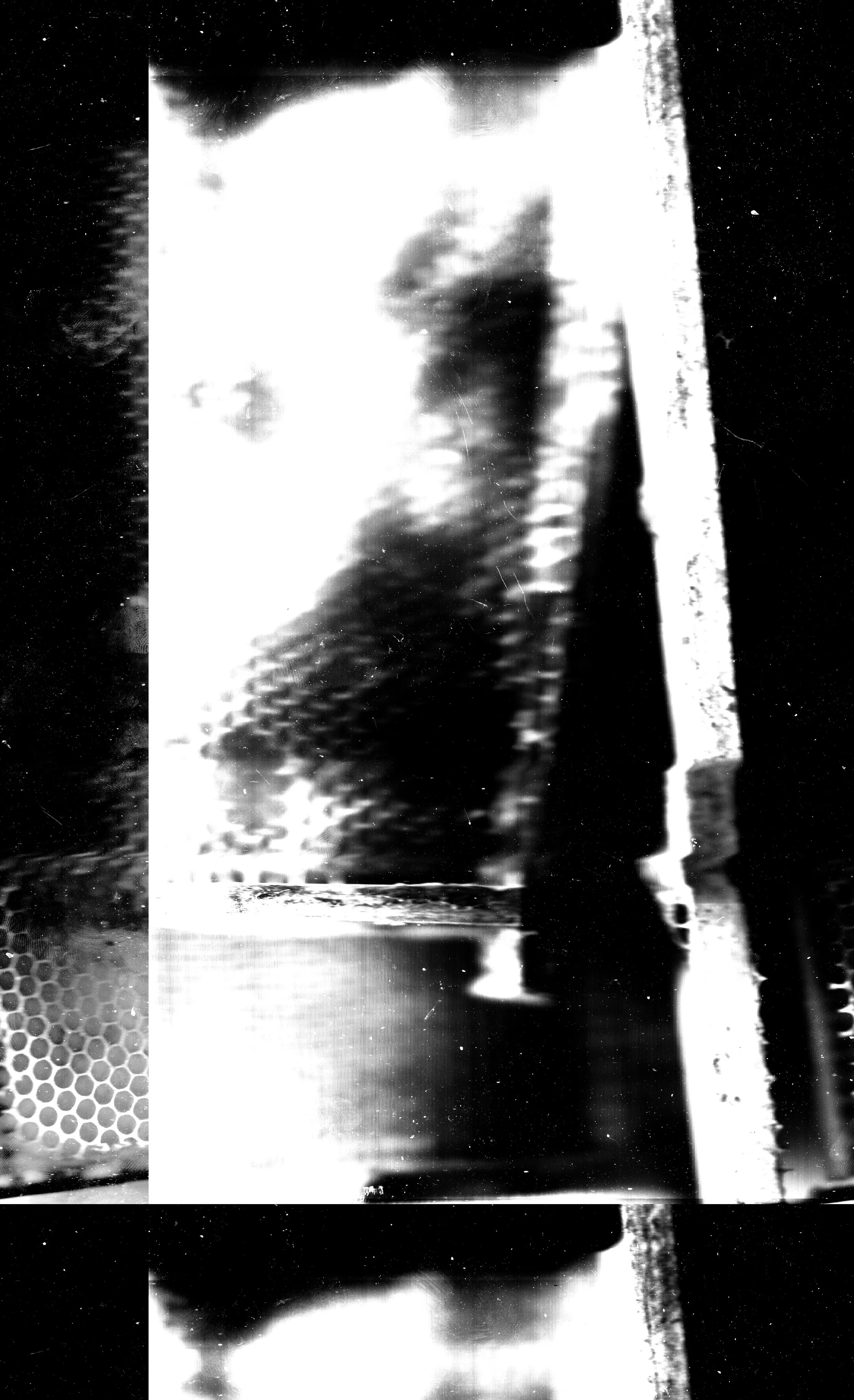 Photo en noir et blanc d'une chaîne de montage ou d'une surface métallique avec des objets ou textures difficiles à distinguer.