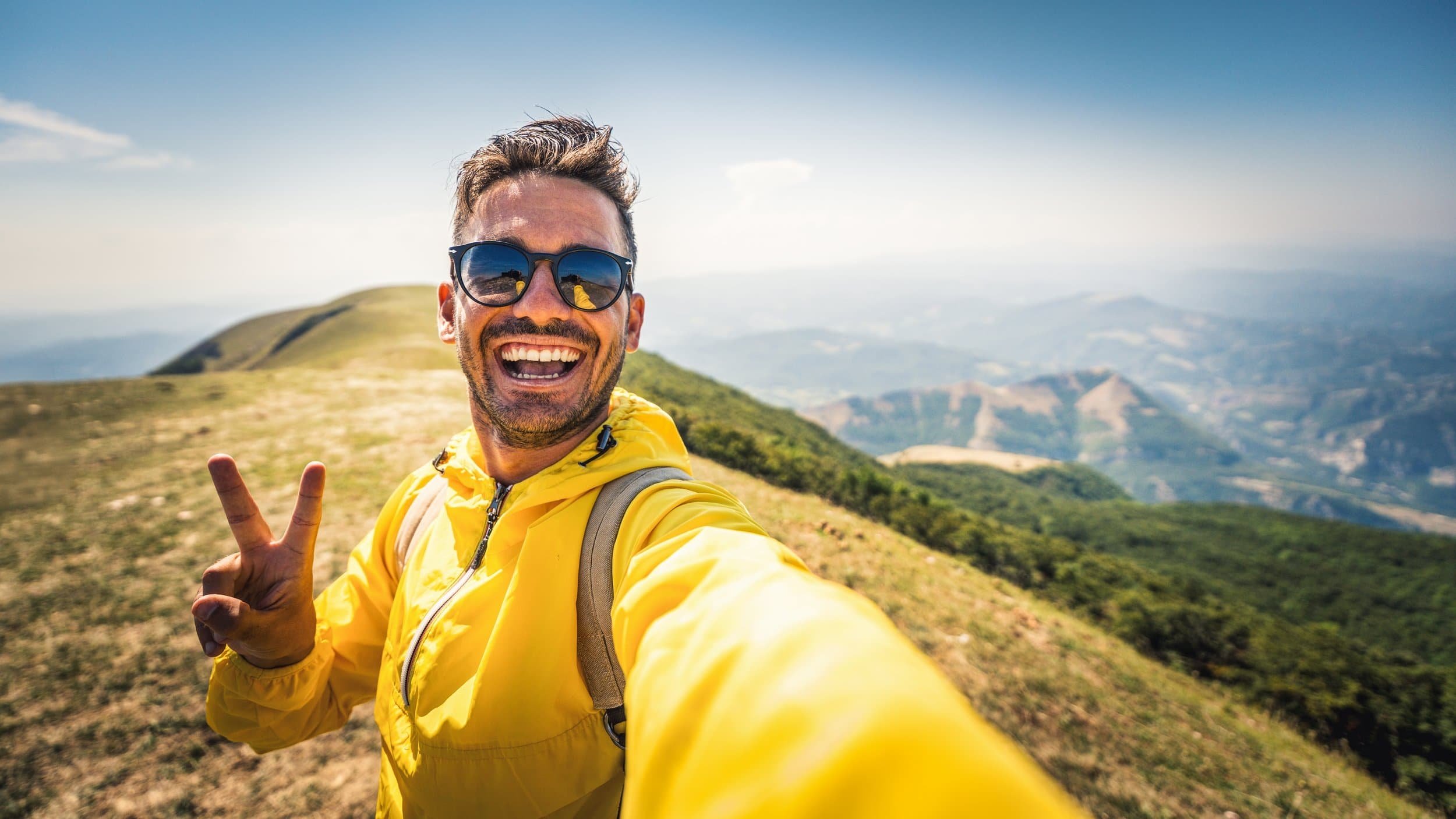 Smiling person in a yellow jacket taking a selfie on a scenic mountain trail—my brain on therapy at Coffee Talk Therapy.