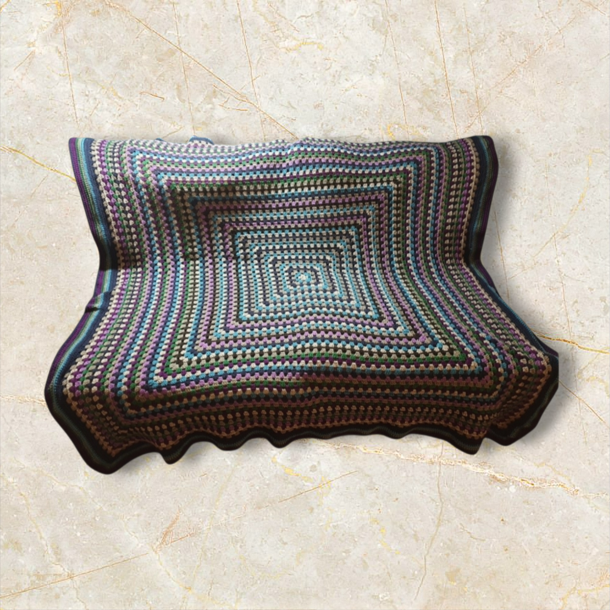 Colorful hand-crocheted square blanket with a concentric square pattern and scalloped edges, laid flat on a beige marble surface.
