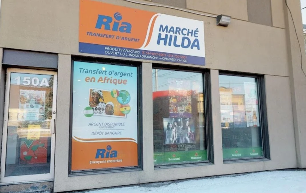 storefront featuring signs for Ria Money Transfer and Marché Hilda, with a poster indicating money transfer services to Africa.