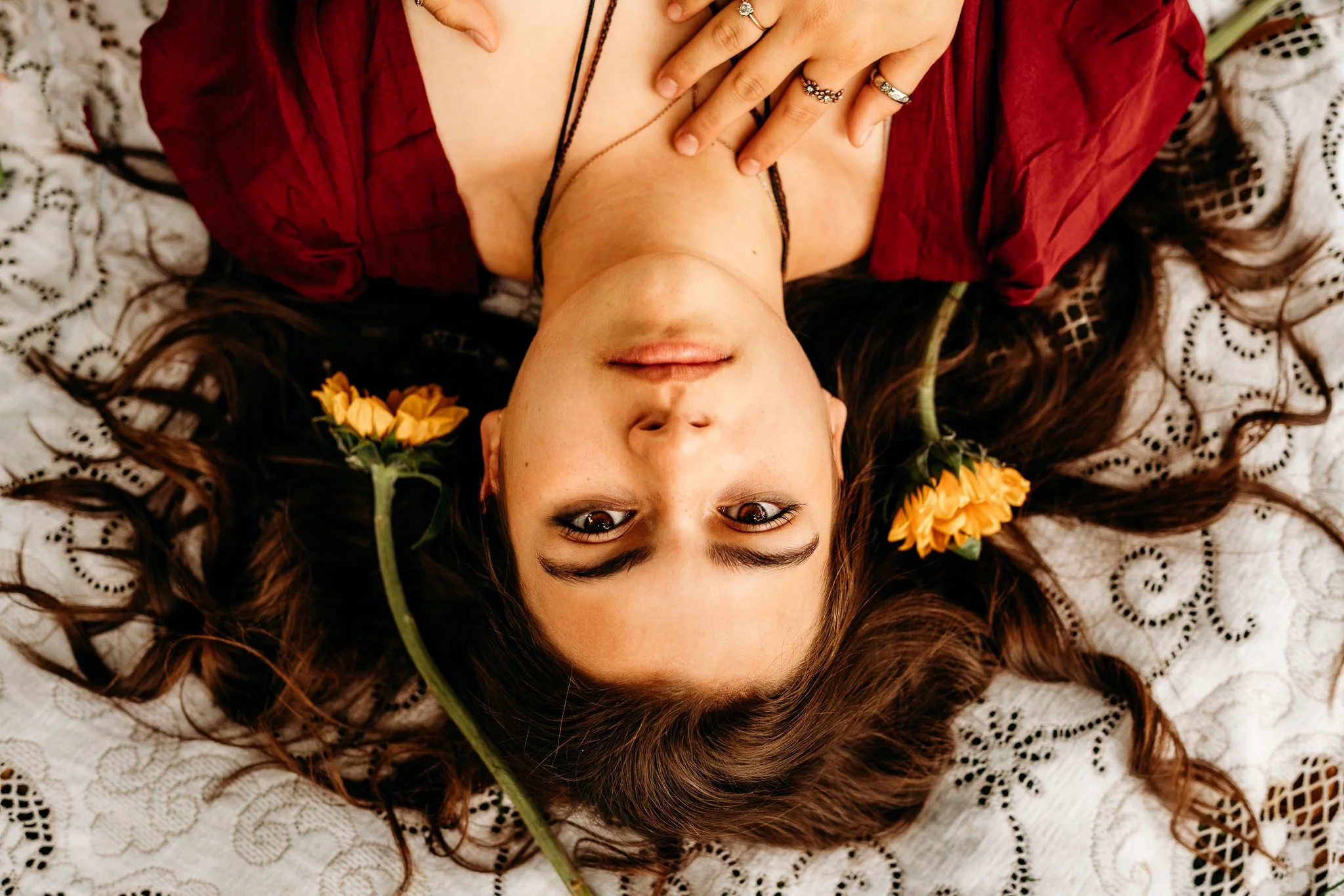 Senior portrait photography of a high school senior lying on a blanket with flowers in her hair, captured outdoors in Oregon