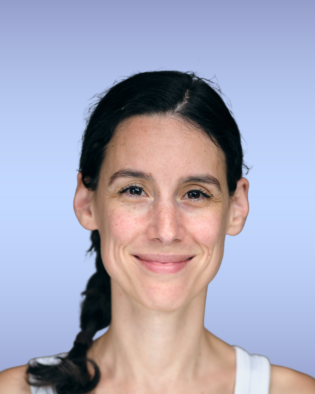 A smiling woman with dark hair styled in a braid, wearing a white top, against a light blue background.