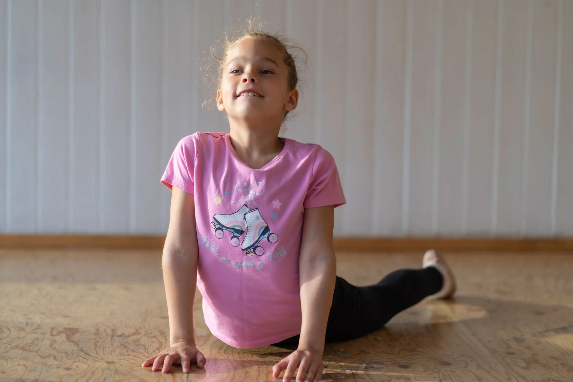 A girl in a casual dance outfit stretches.