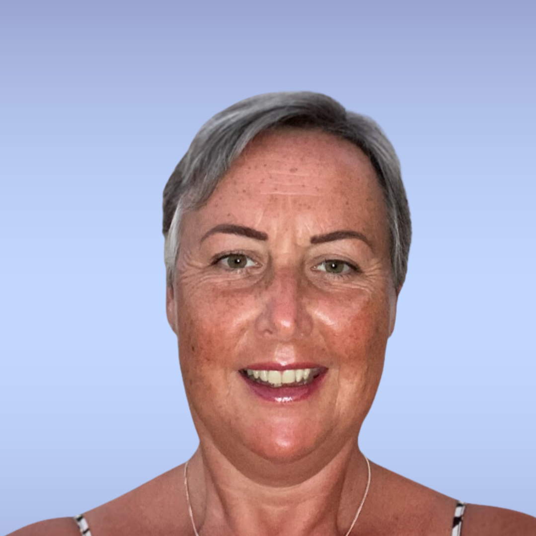 Profile photo of a middle-aged woman with short gray hair, wearing a sleeveless striped top and a silver necklace, smiling with a light blue background.