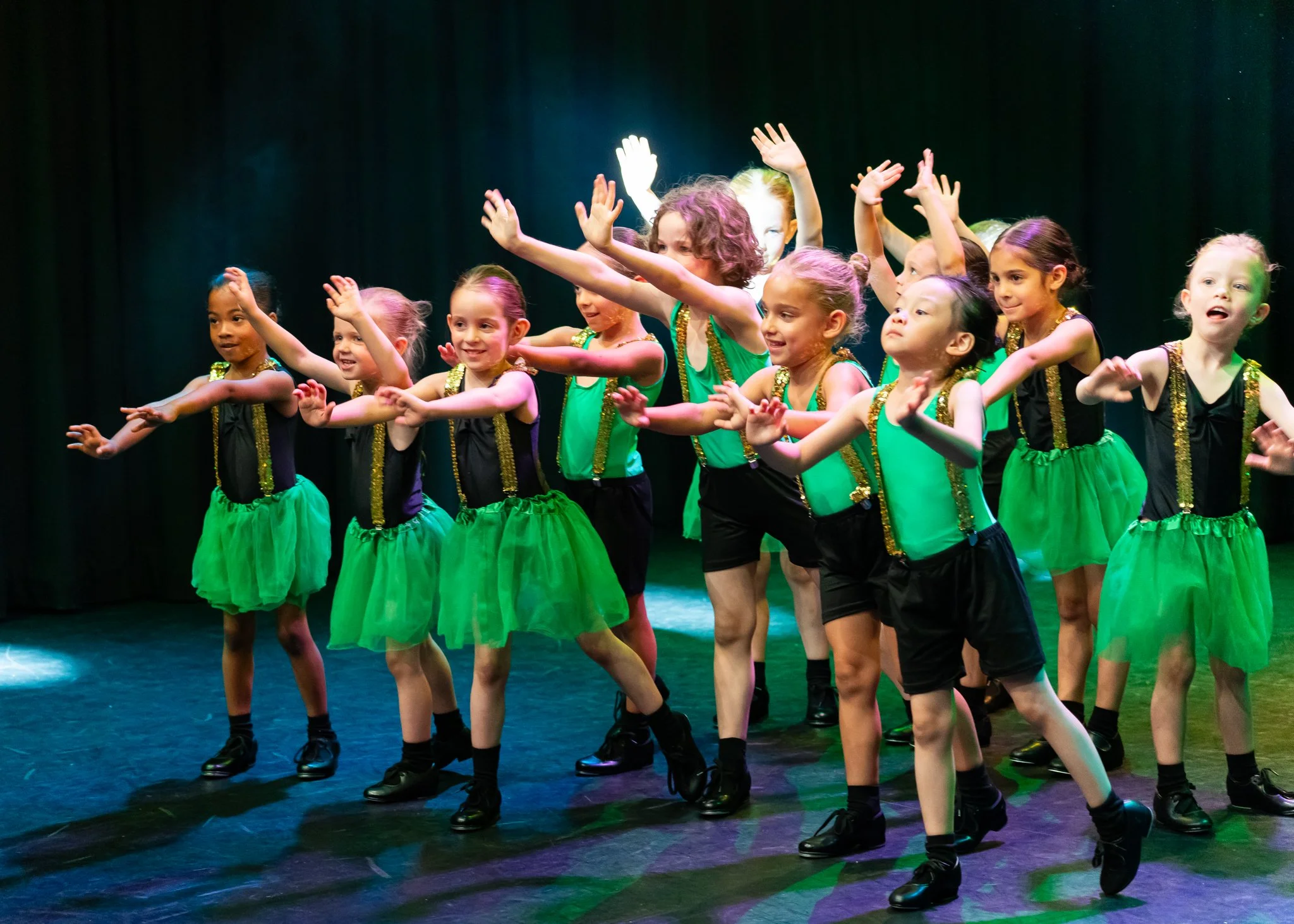 Children in colorful dance costumes performing on stage during a dance recital