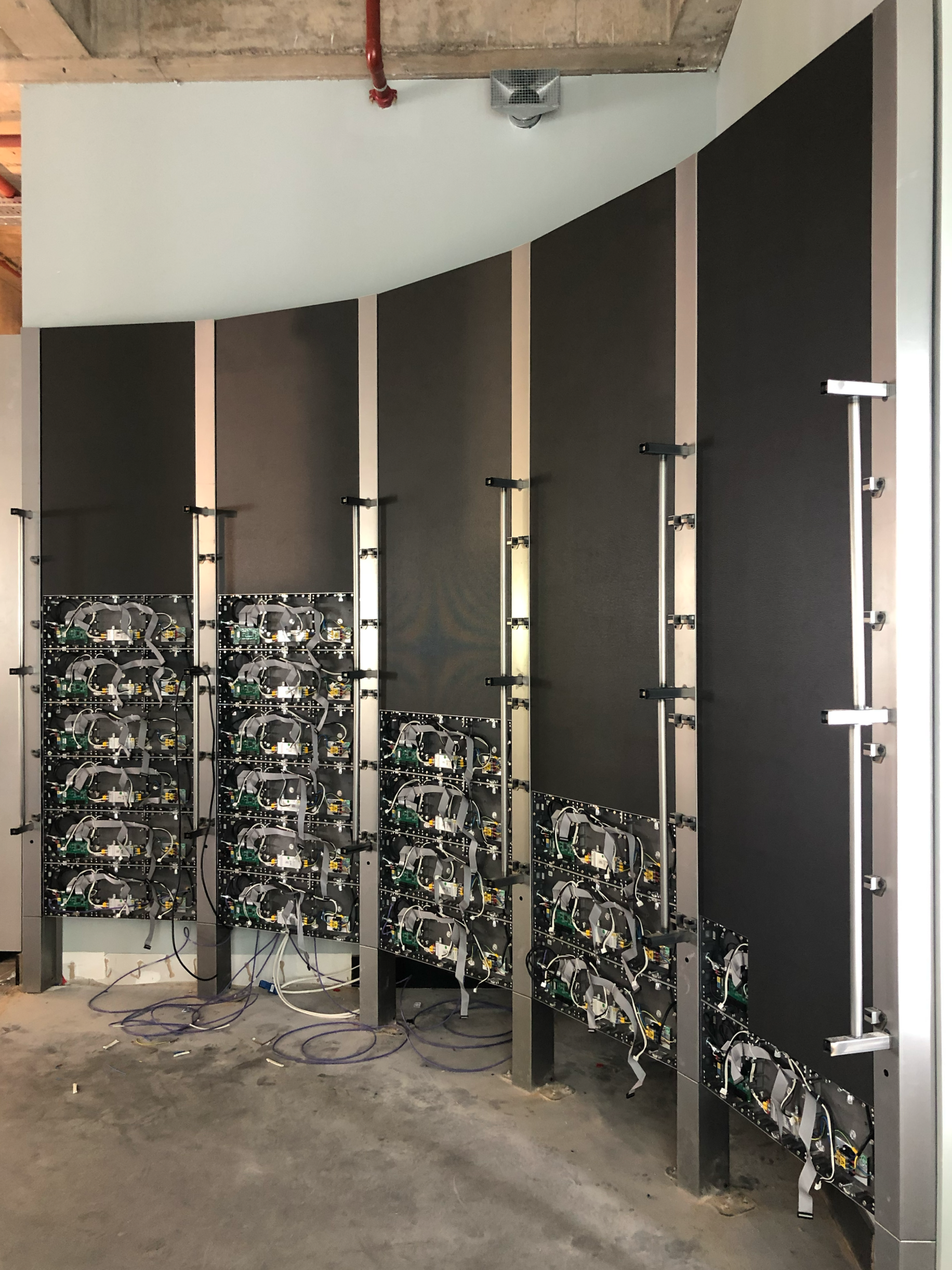 Two large black metal server racks with visible electronic components and wiring on a concrete floor in a data center or server room.