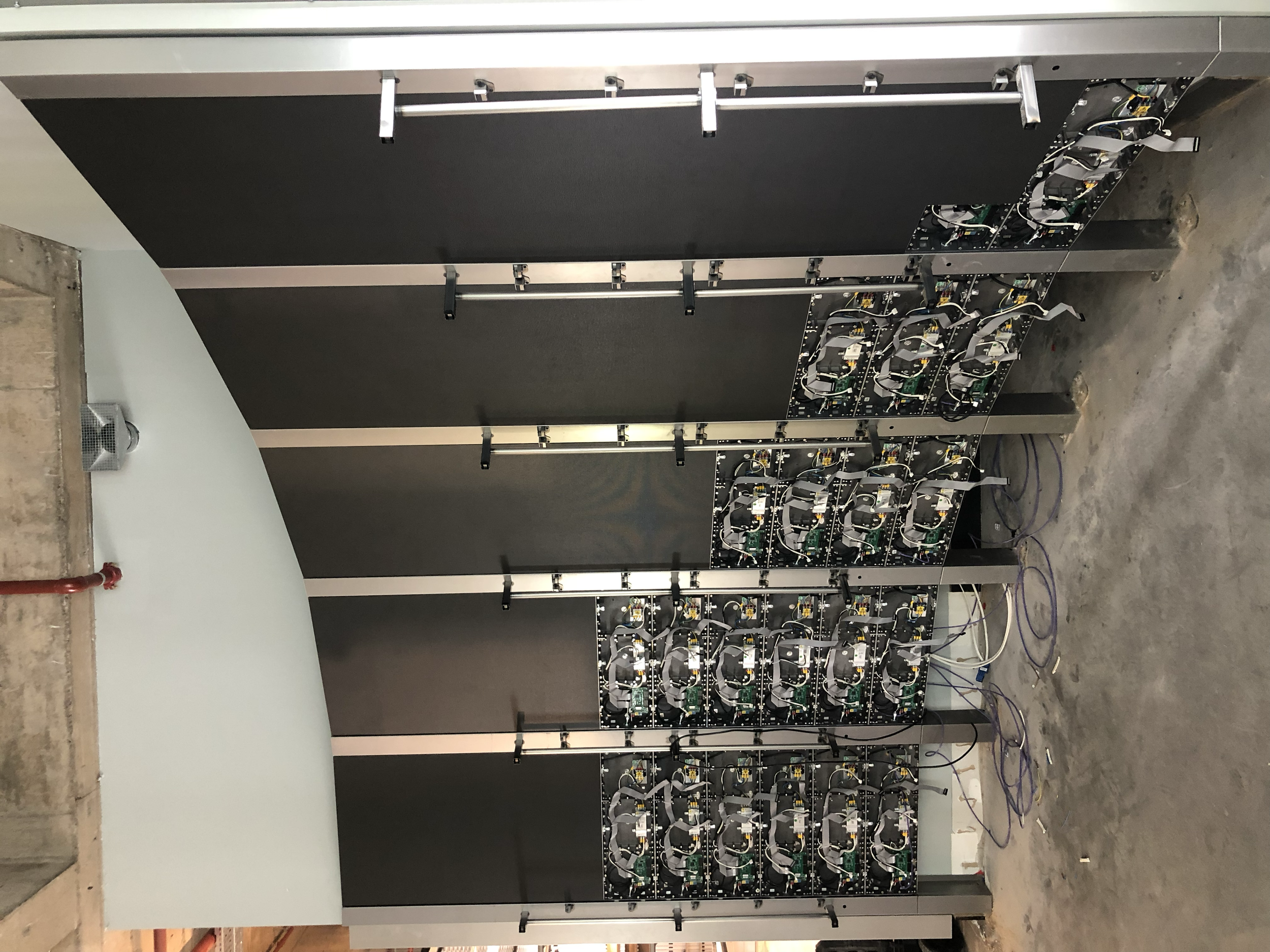 Two large black metal server racks with visible electronic components and wiring on a concrete floor in a data center or server room.