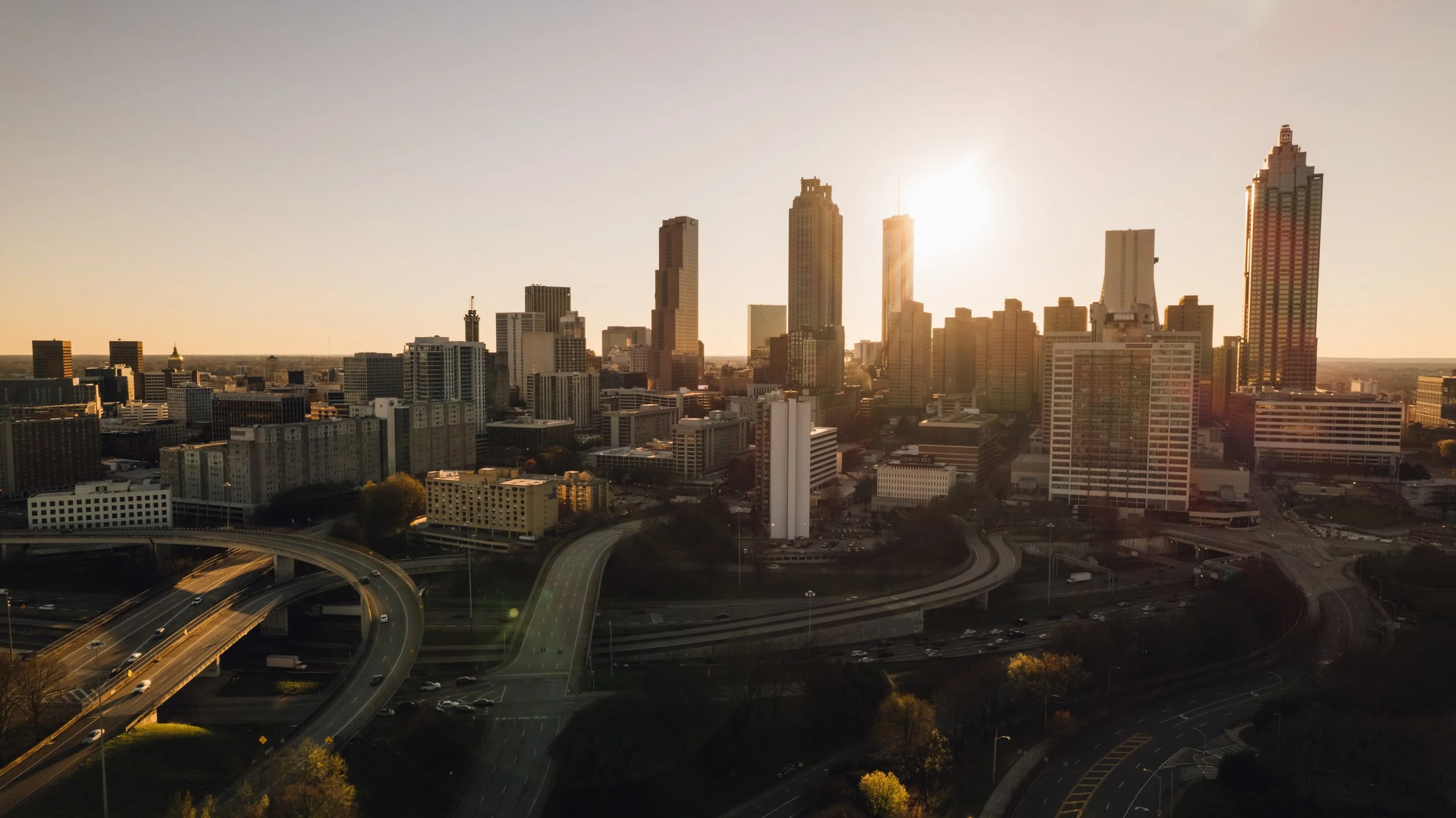 Sunset over a city skyline with tall skyscrapers, highways, and roads in Atlanta, Georgia.