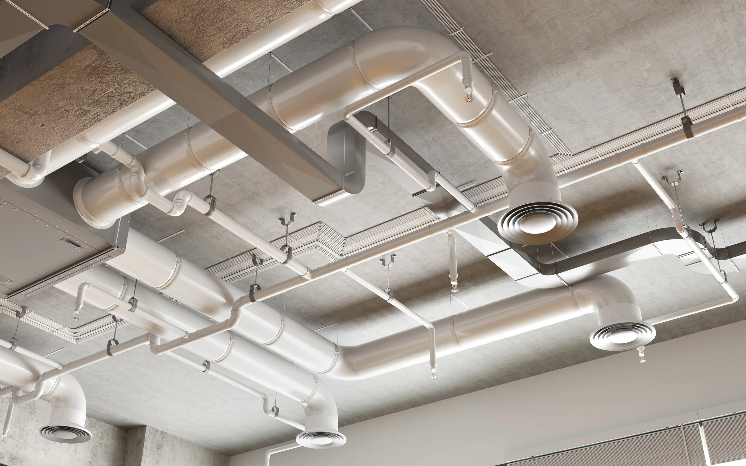 Ceiling with exposed white ducts, pipes, and vents in an industrial or commercial building.