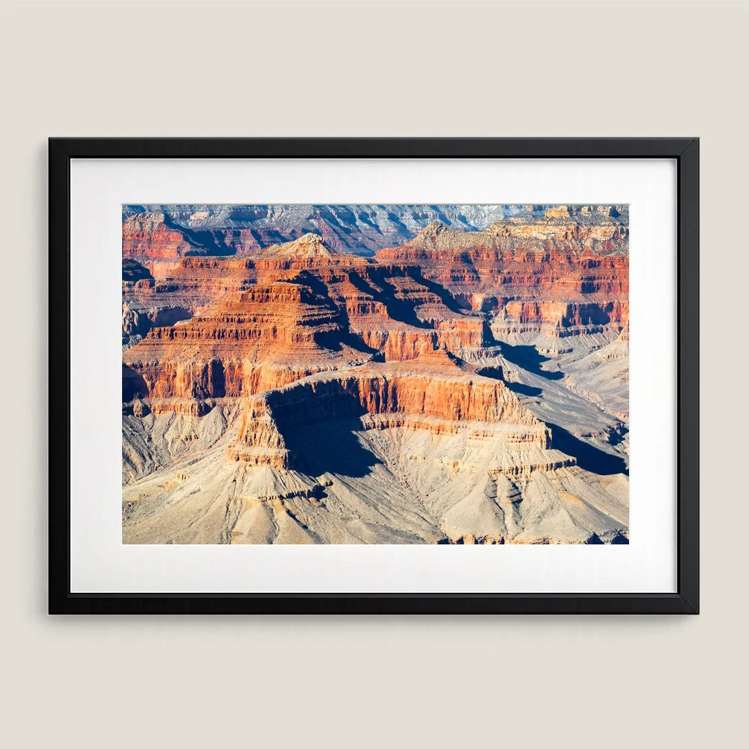 Framed Grand Canyon landscape print with black frame and white mat, featuring layered sandstone mesas and buttes.