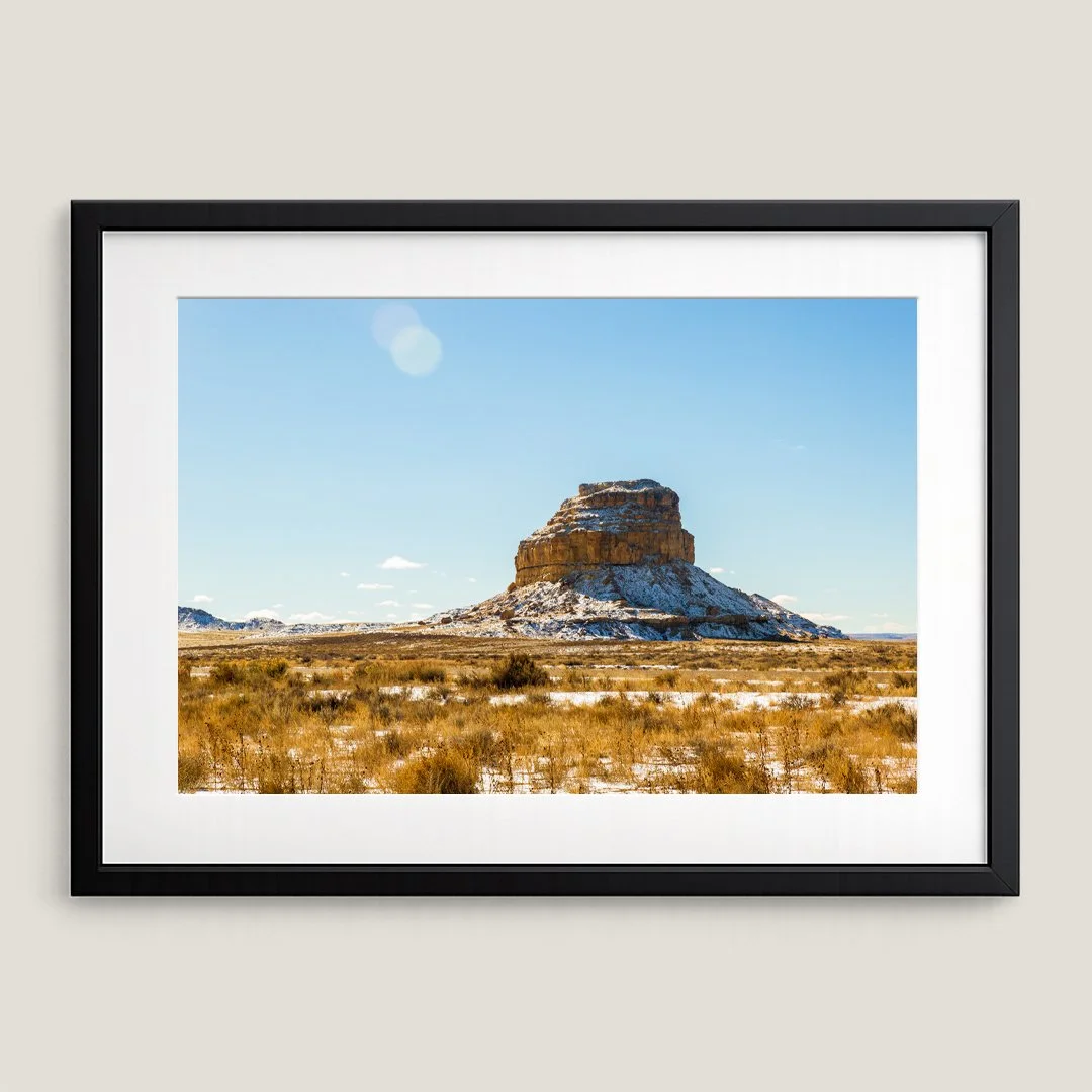 Framed Southwest desert butte print with black frame and white mat, featuring a snow-dusted rock formation.