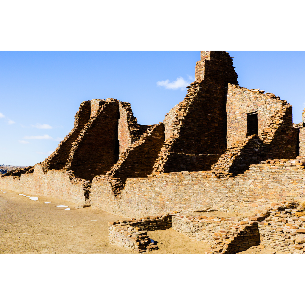 Sunlit stone structures of Chaco Canyon showcasing ancient architecture in the New Mexico desert.