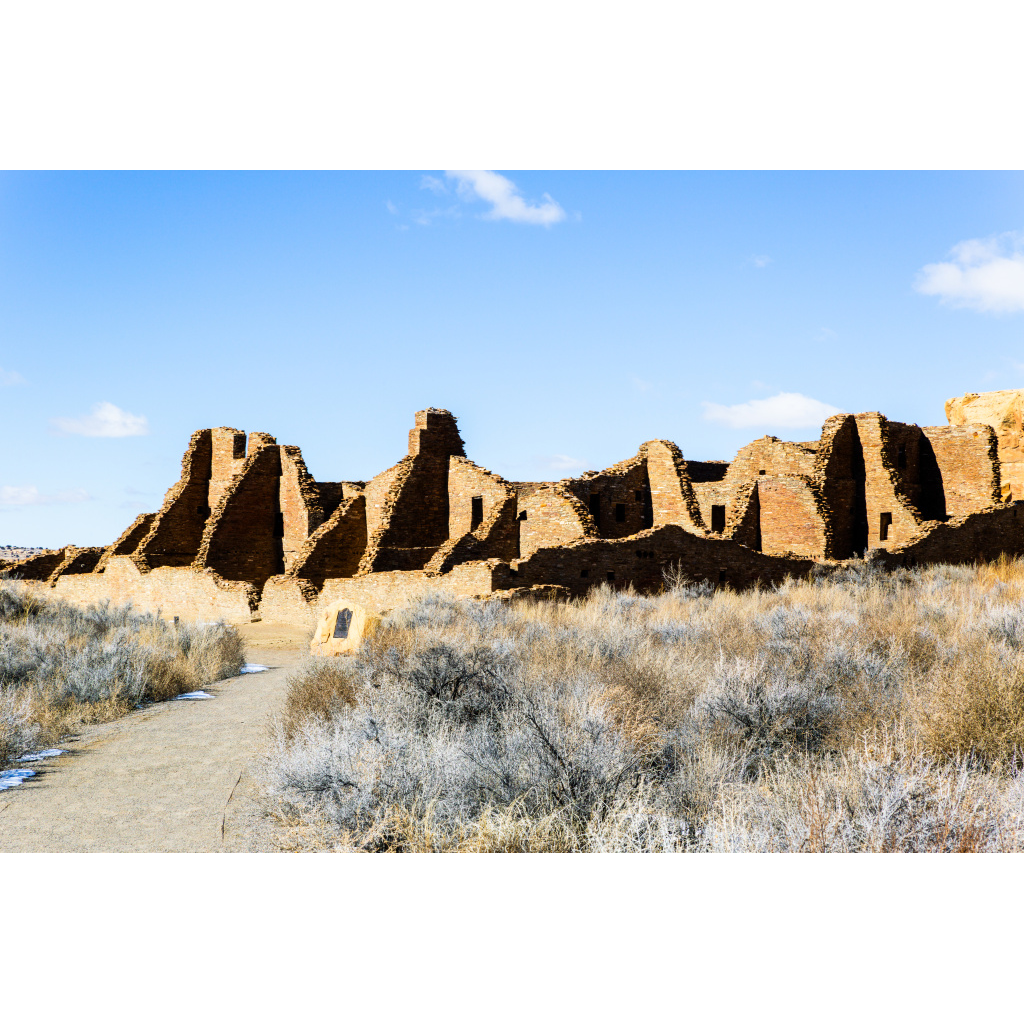 Historic stone ruins of Chaco Canyon under a clear blue sky in the New Mexico desert.