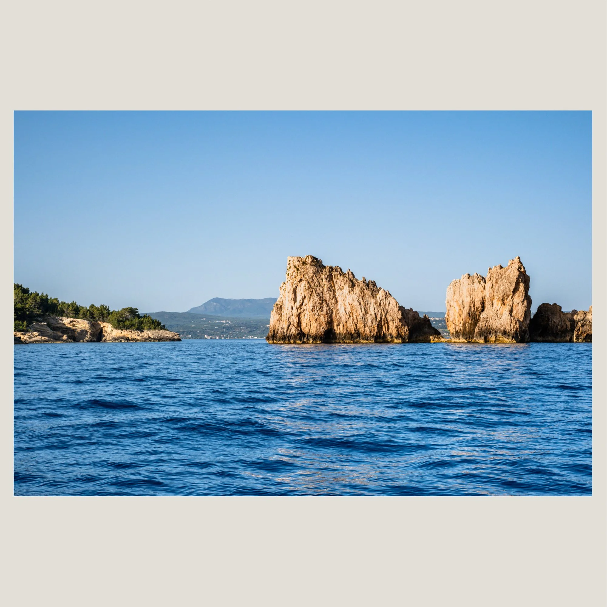 Rock formations rising from the sea in Navarino Bay, Messinia, Greece under a clear sky.