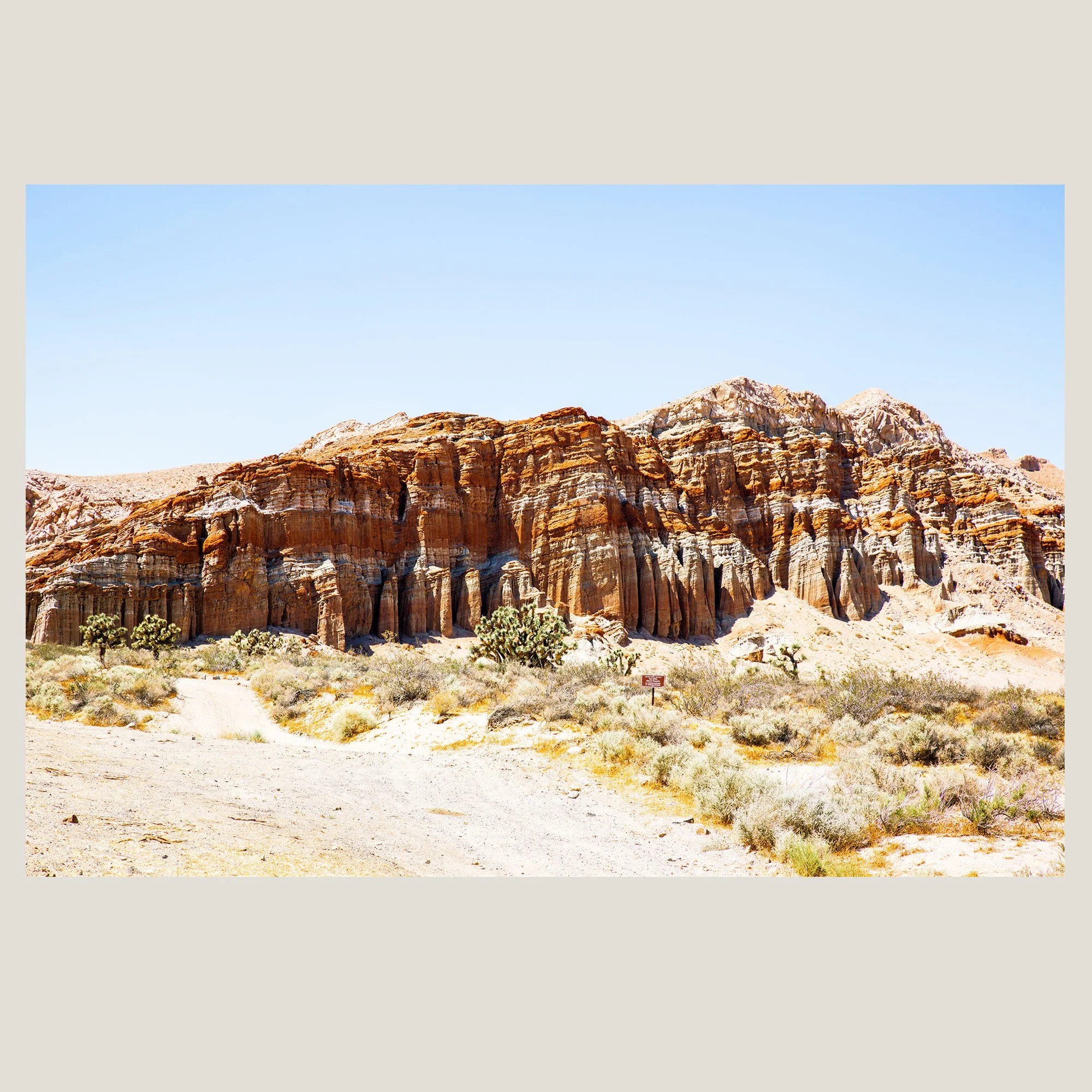 Towering red rock cliff formation rising above desert vegetation in the American Southwest.