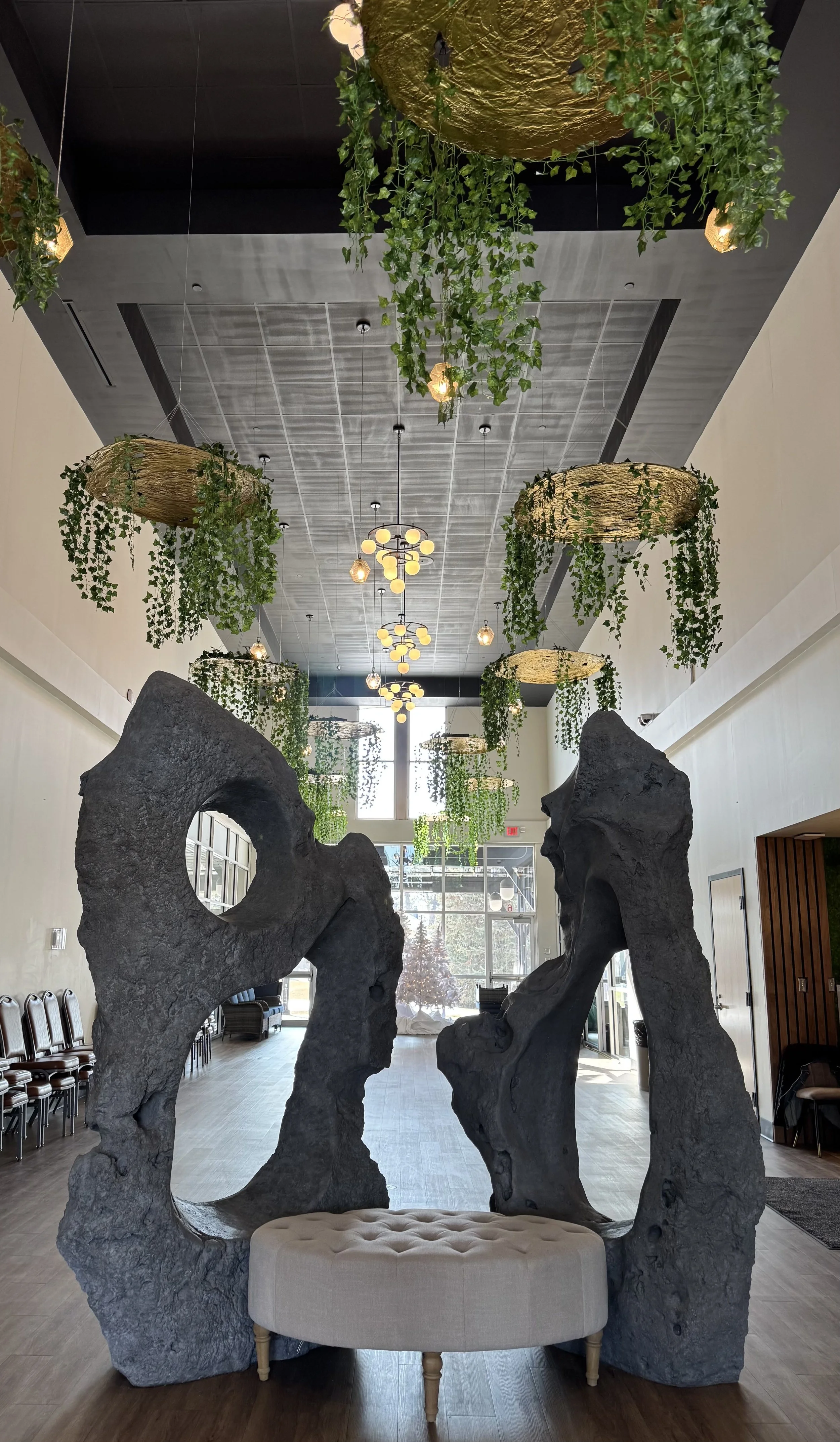 atrium with greenery hanging from ceiling and a big sculpture