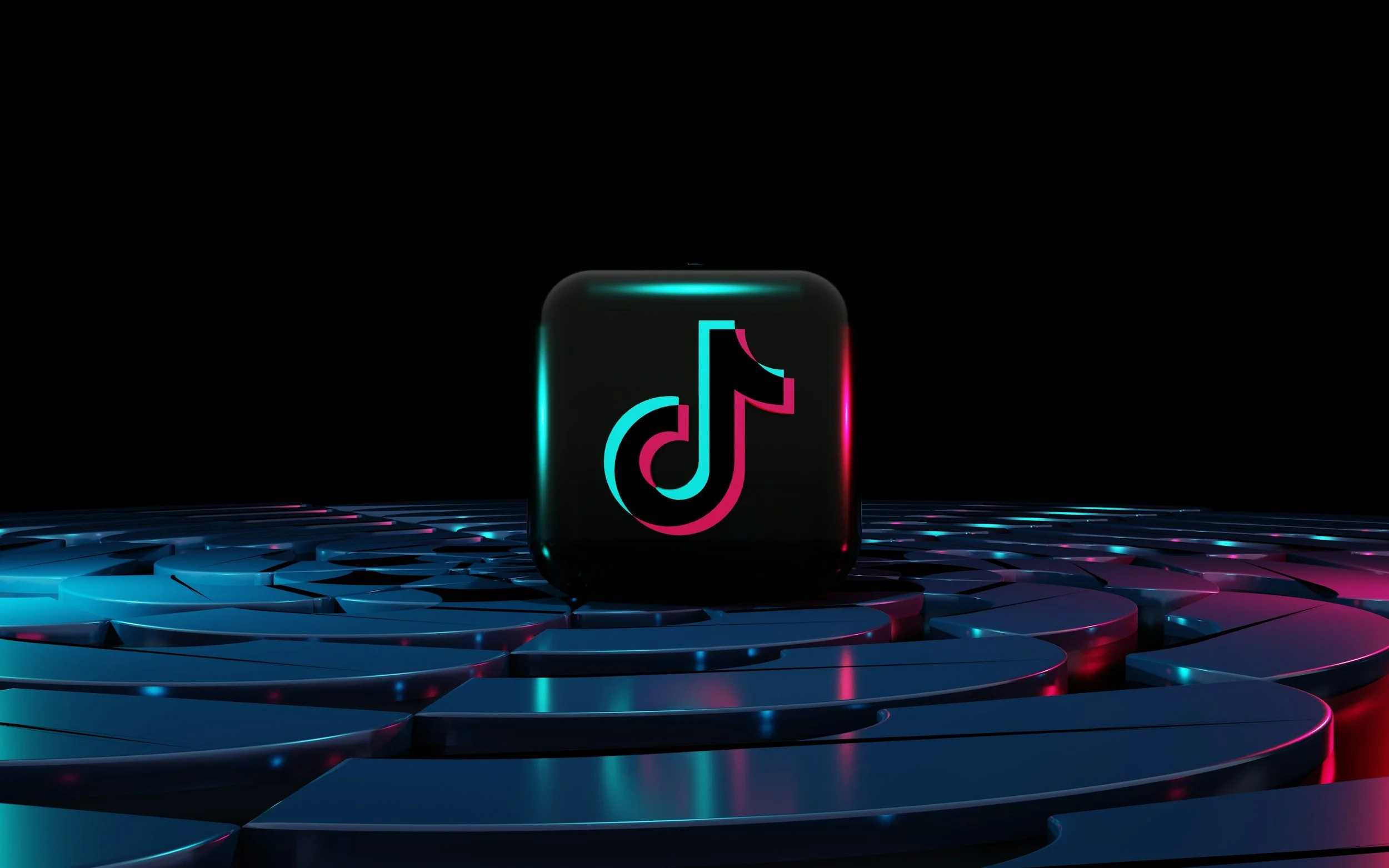 A glowing digital icon of the TikTok app on a black cube, with a futuristic patterned surface illuminated by blue and pink lights, against a dark background.