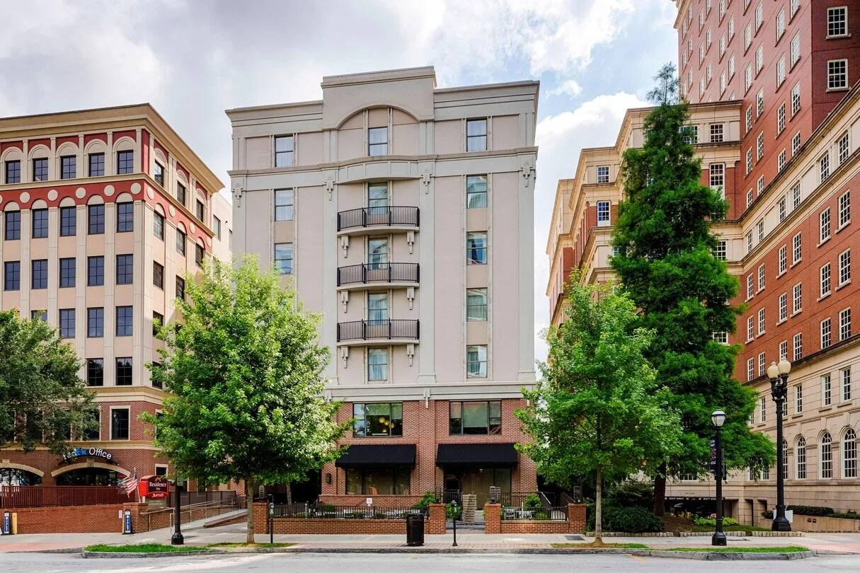 Residence Inn by Marriott Atlanta Midtown/Peachtree. Tall beige and red brick buildings with green trees in front, street view with sidewalk and street lamps.