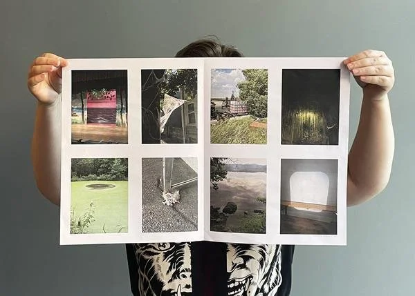 Person holding a sheet with eight photographs of various outdoor scenes, including a pink playground, a boat, a park bench, a wooded path, a backyard pond, a sidewalk with a stick, a lakeside view, and an empty room with a window.