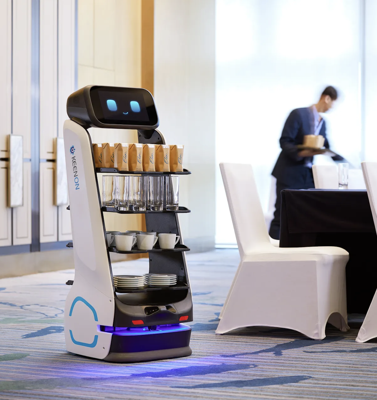 Un robot de livraison servant du café, des verres, des tasses et des assiettes dans l’espace de restauration d’un hôtel ou d’un centre de conférence.