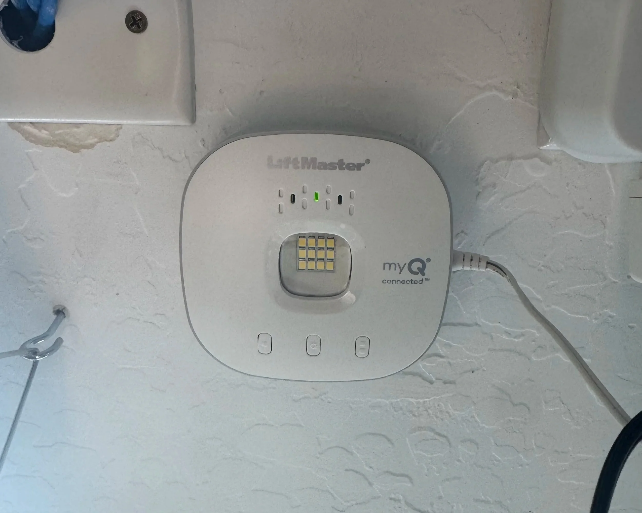 Wireless medical device mounted on a textured wall with indicator lights, connected to a power source.
