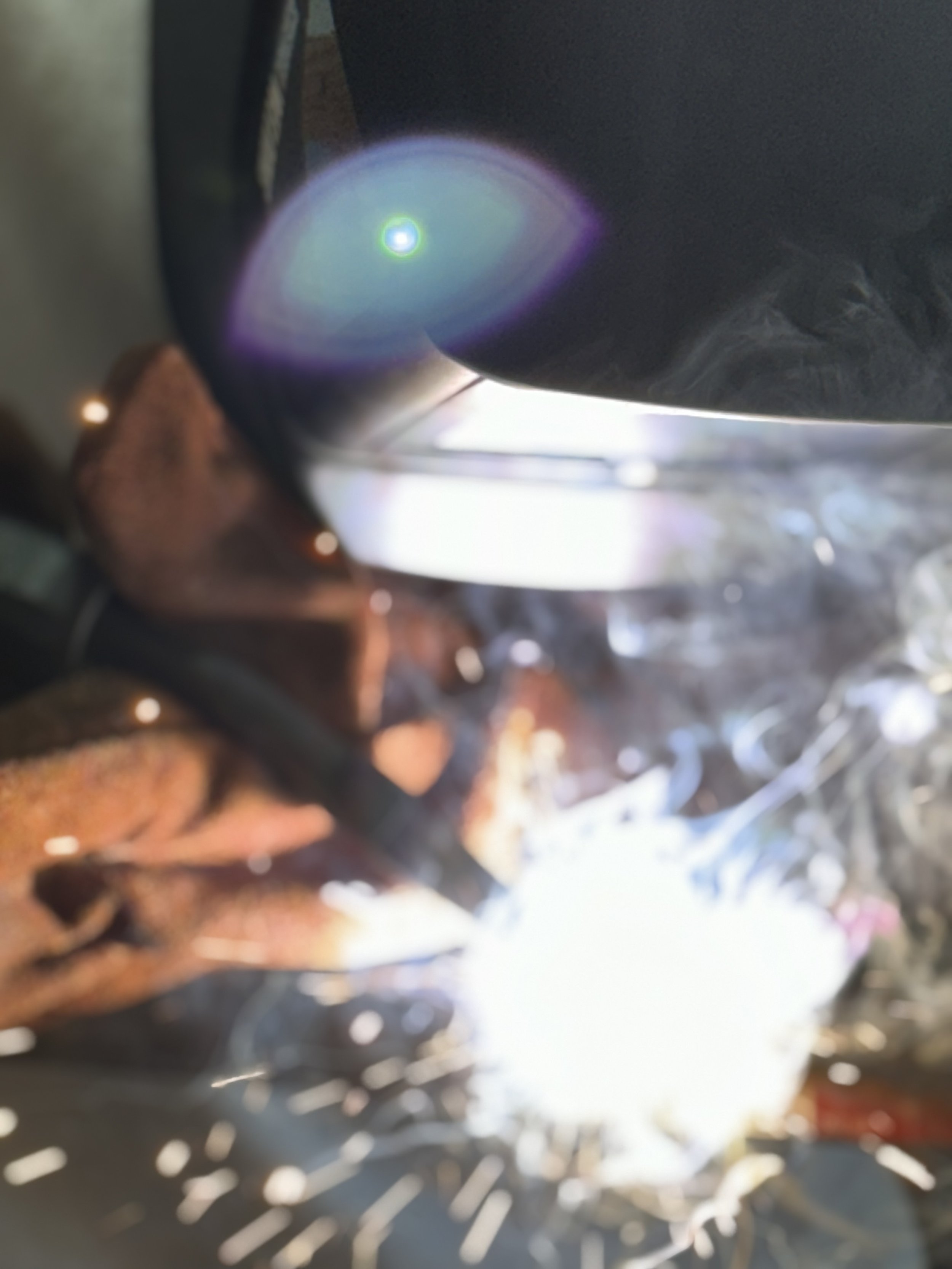 Close-up of a welding process with bright light, sparks, and metalwork in progress.