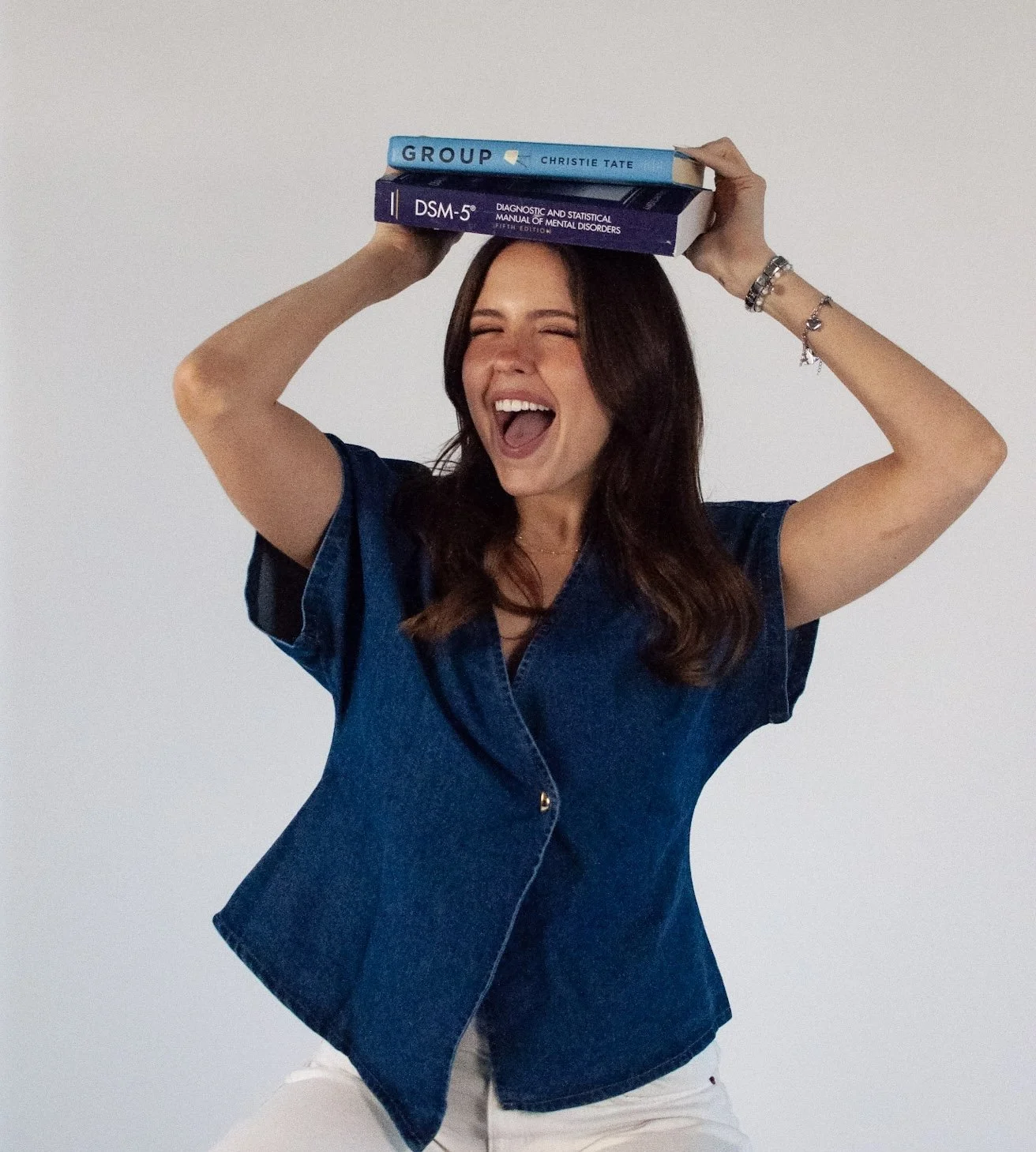 Ava Parent, LICSW, therapist at Soft Place Therapy, smiling with books to reflect a warm and approachable style in working with teens and young adults
