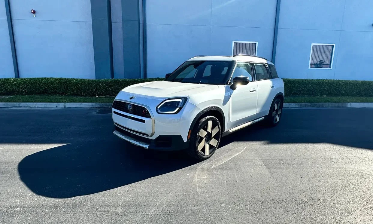 White SUV parked on asphalt near a modern building with blue walls.