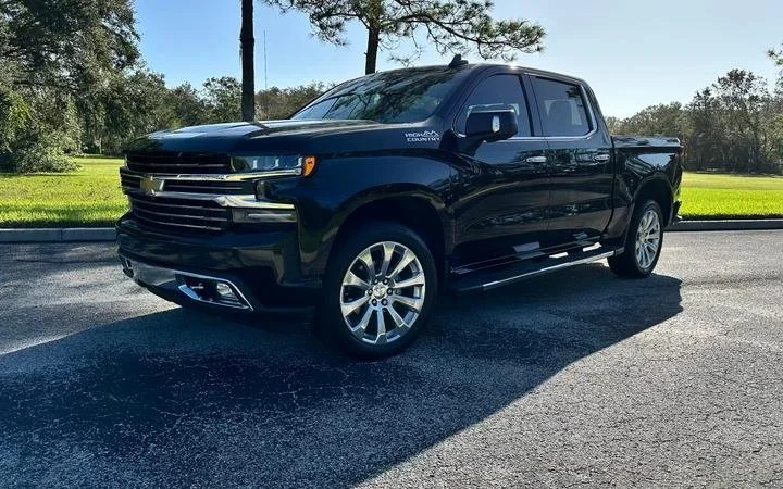 Black Chevrolet Silverado High Country truck parked outdoors on a sunny day.