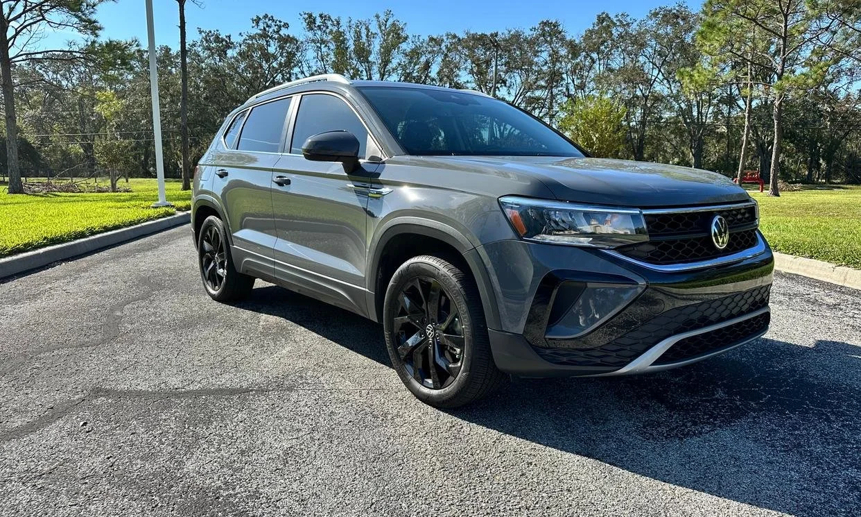 Gray Volkswagen SUV parked on a road, surrounded by trees and grass.