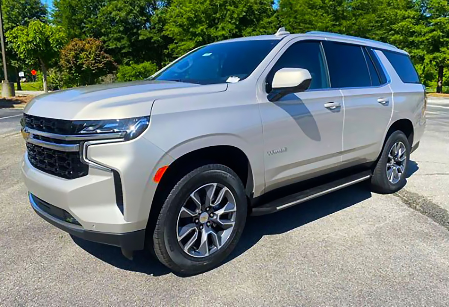 Silver SUV parked on a street with trees in the background.
