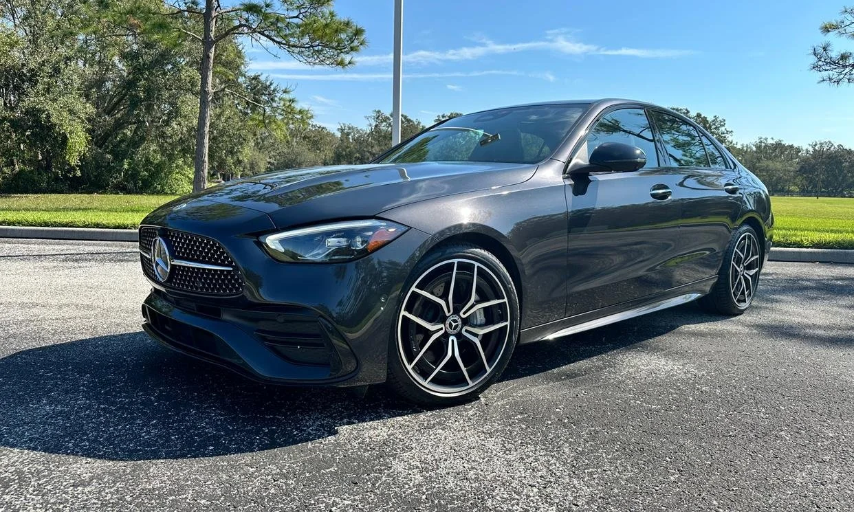 Luxury car parked on asphalt with trees in the background