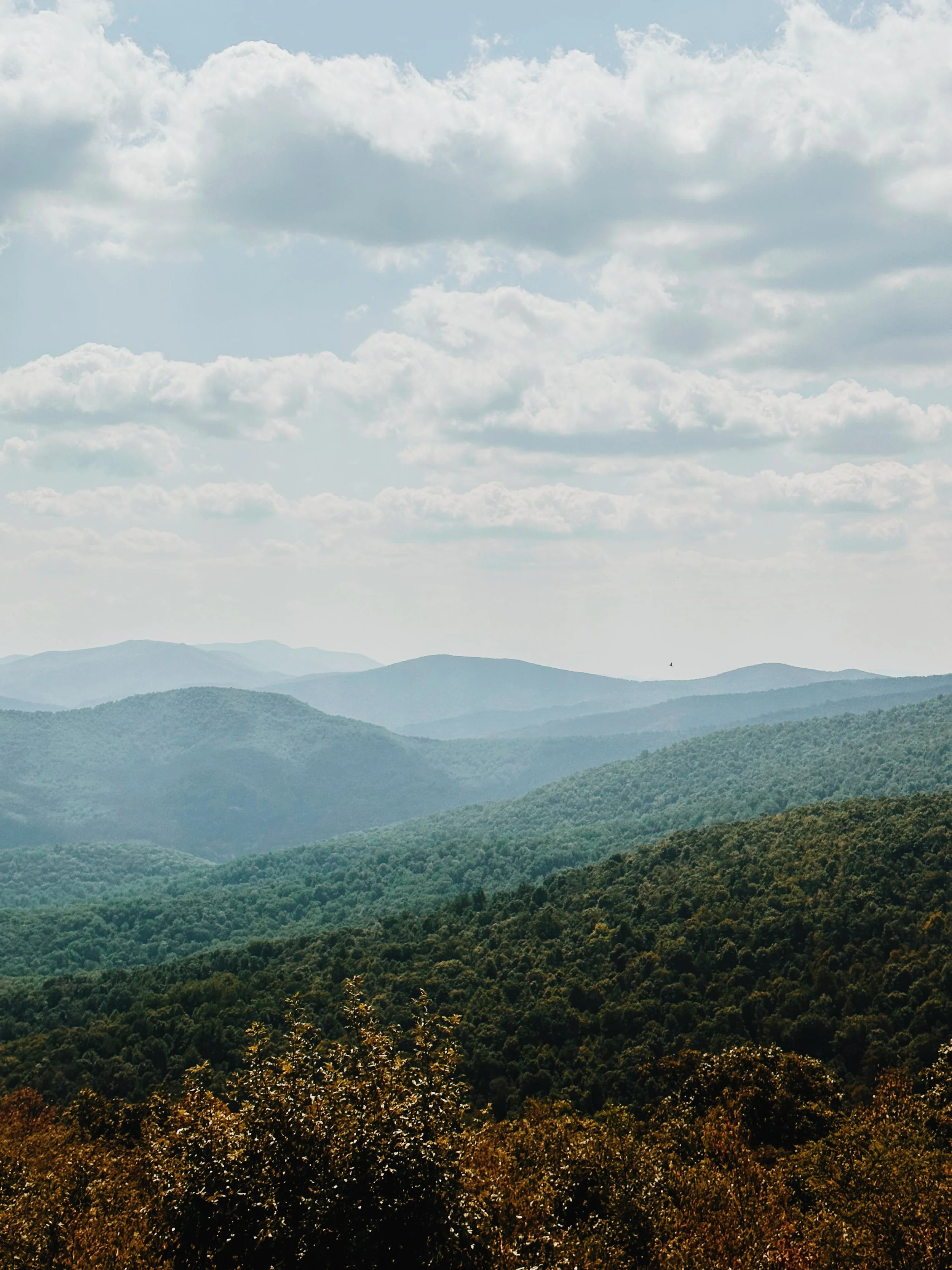 Scenic view of rolling green mountains under a partly cloudy sky.