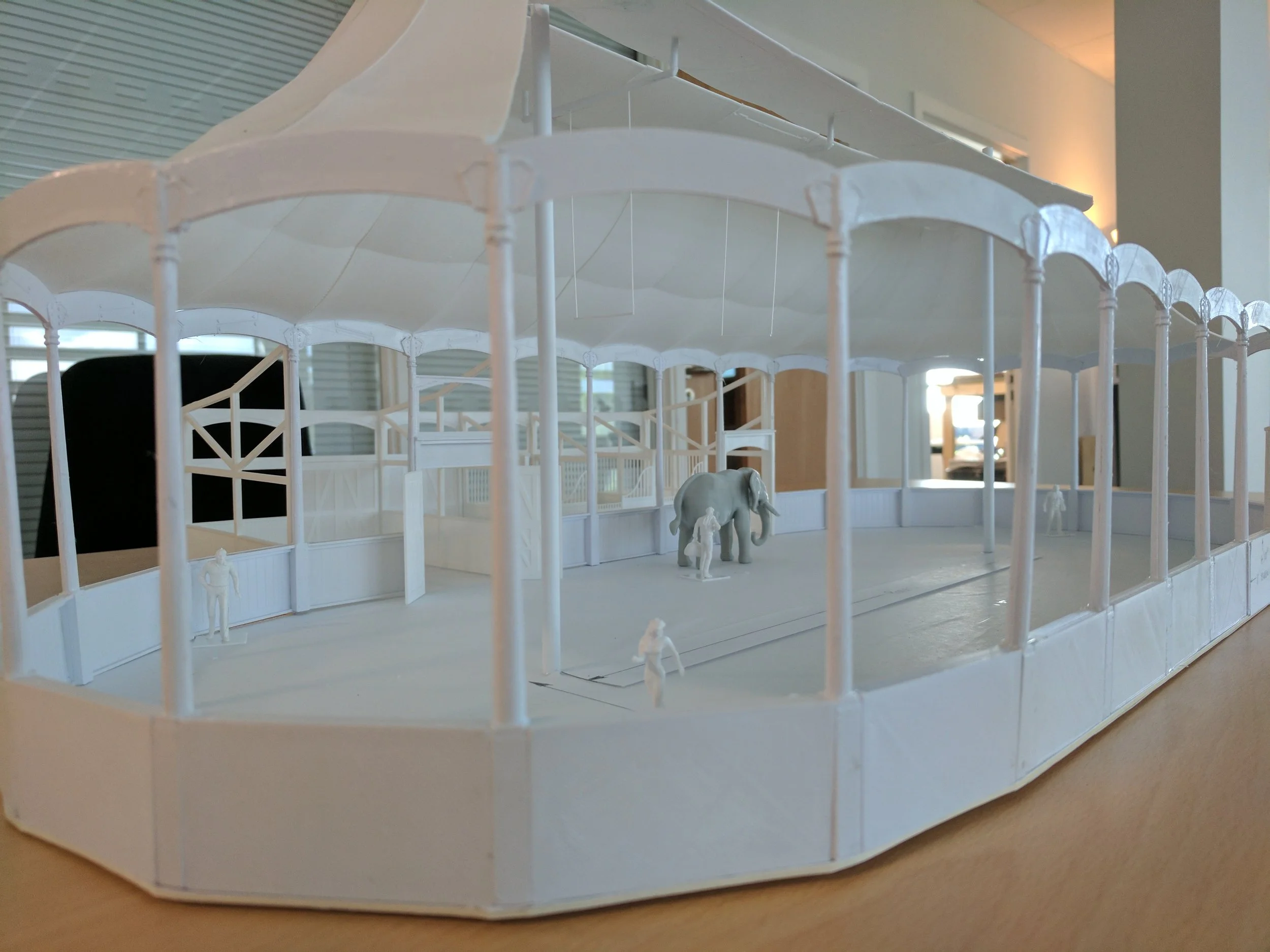 Architectural model of a circus tent with small figurines and an elephant inside.