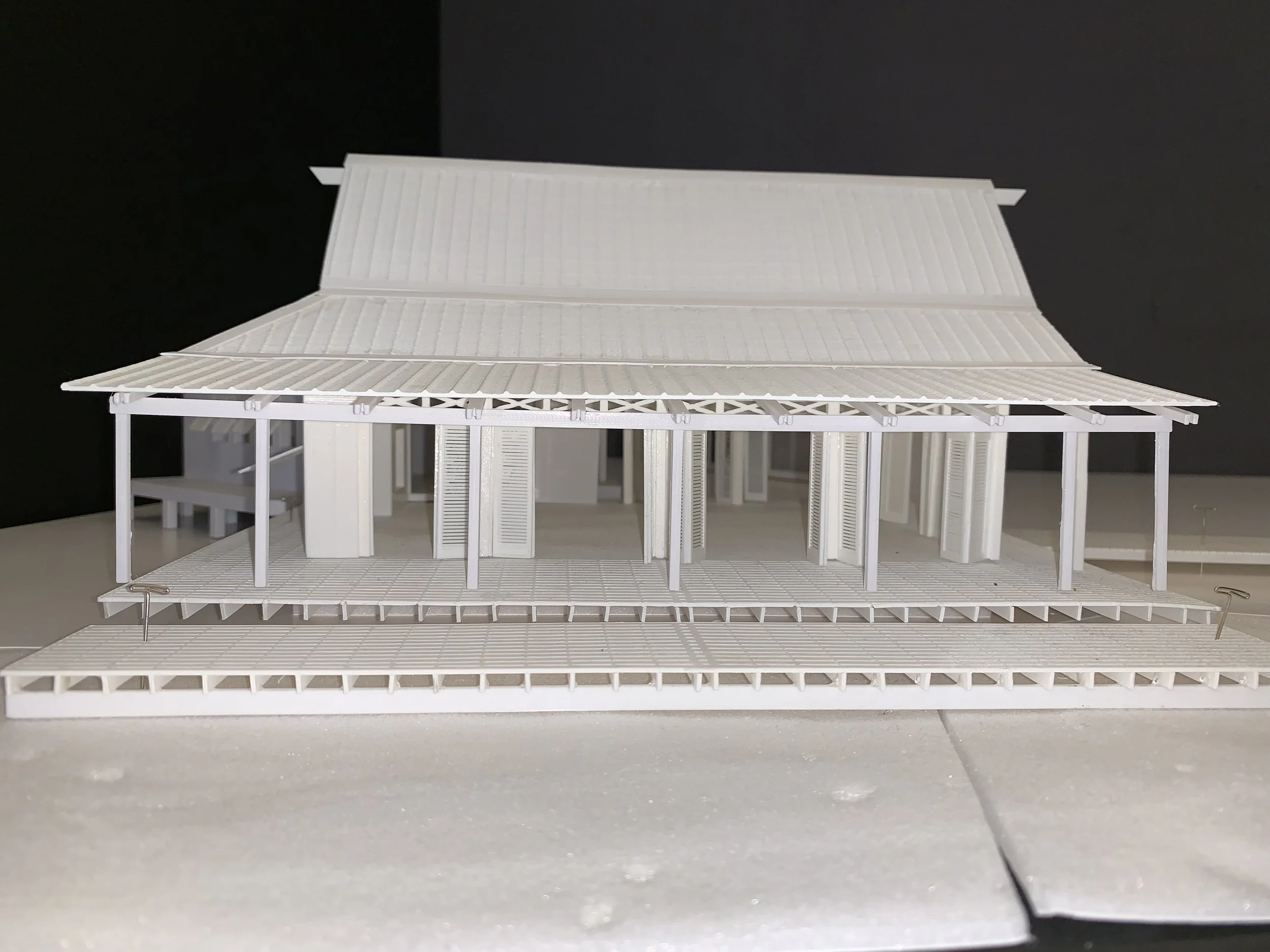 White architectural model of a traditional Asian-style building with a curved roof and open sides, set on a white surface.