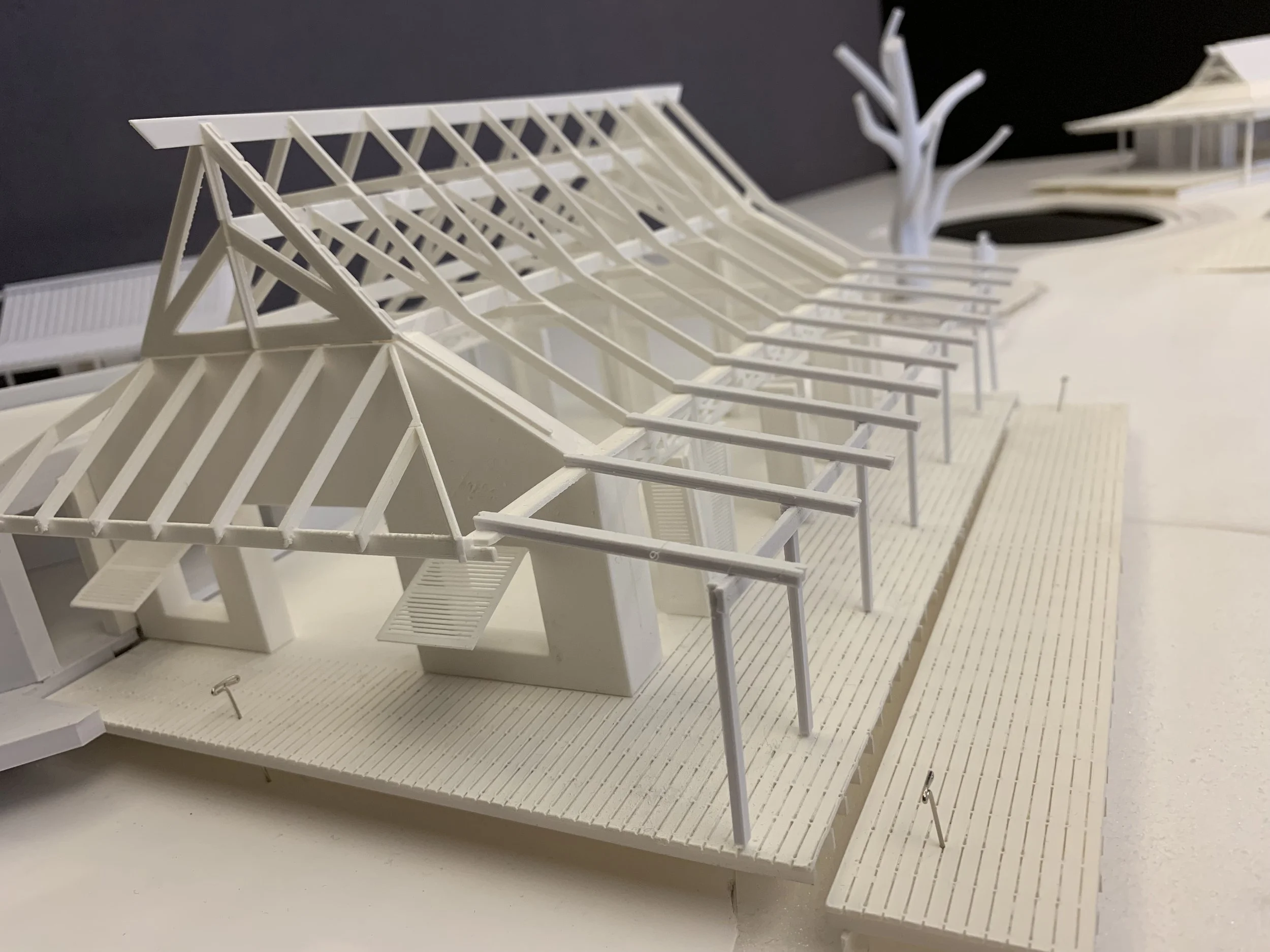 Architectural model of a large building with a sloped roof, open framework, and outdoor deck areas.