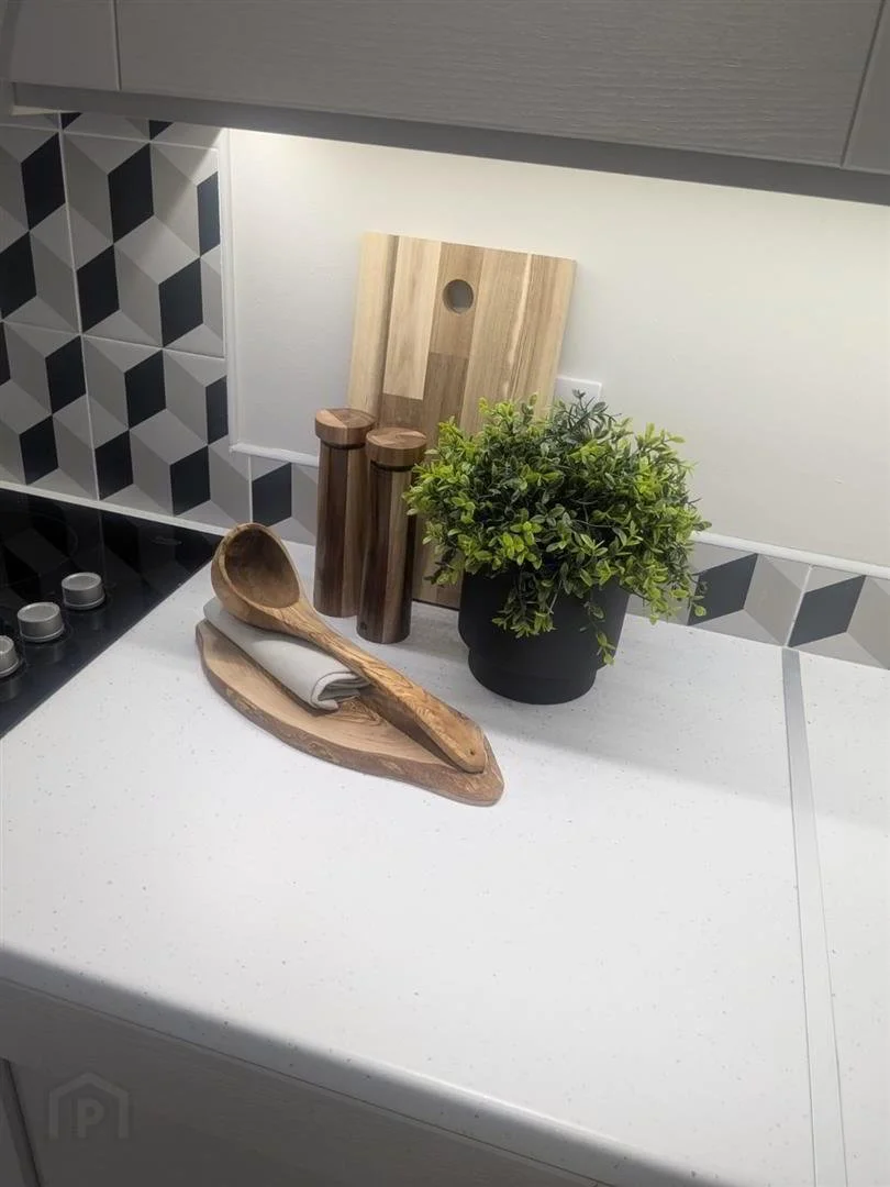 Kitchen countertop with wooden utensils, a potted plant, and cutting boards.