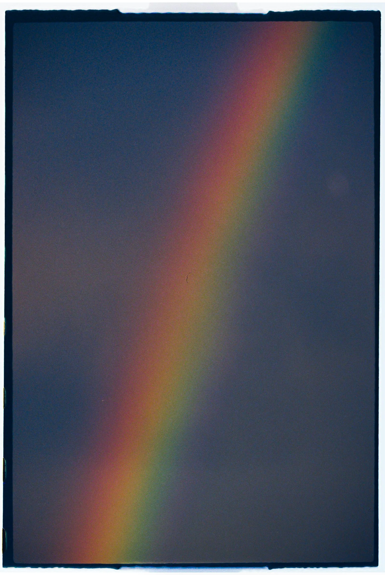 Un arco iris en un cielo oscuro con tonos grises y azules.
