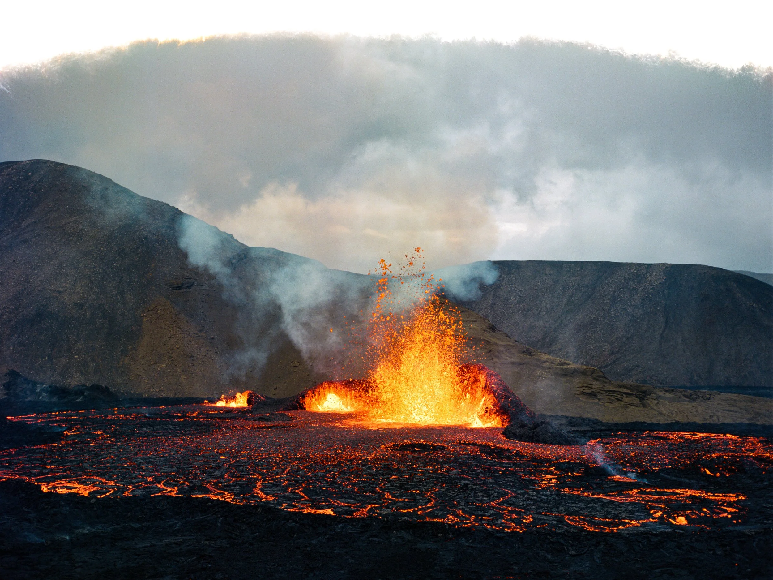 Erupción volcánica con lava, humo y cenizas en un paisaje montañoso