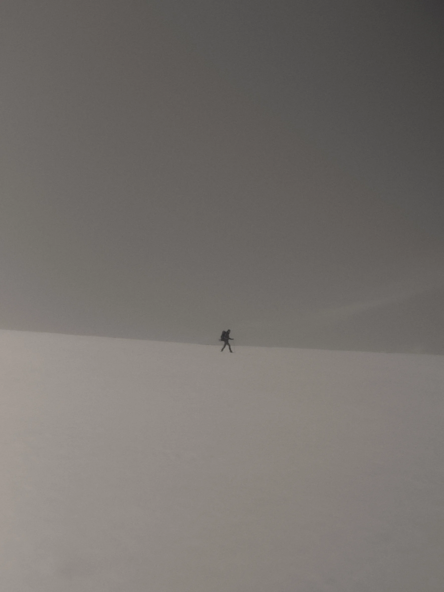 Esquiador en la nieve, con cielo gris oscuro y horizonte brumoso.