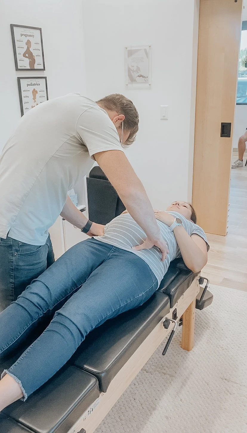 Doctor performing a physical exam on a woman lying on an examination table in a medical clinic