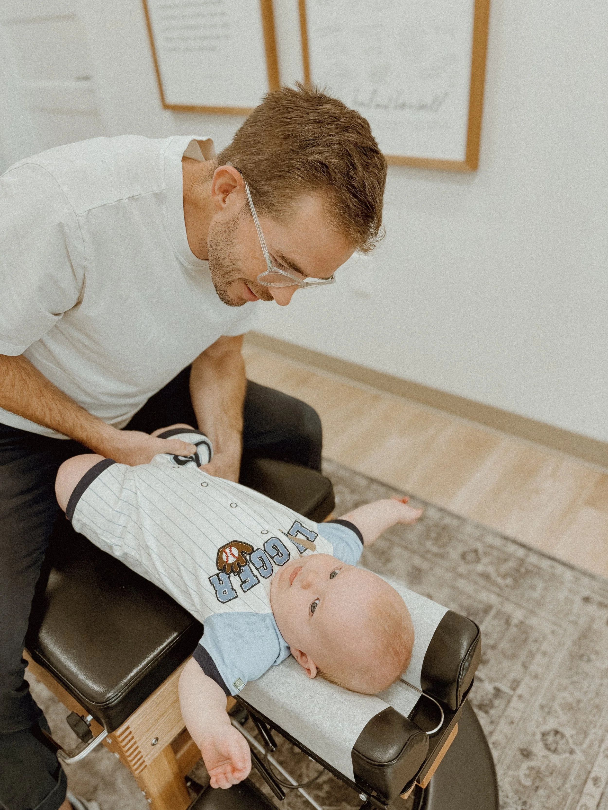 A doctor checking a young child's leg in a medical office.