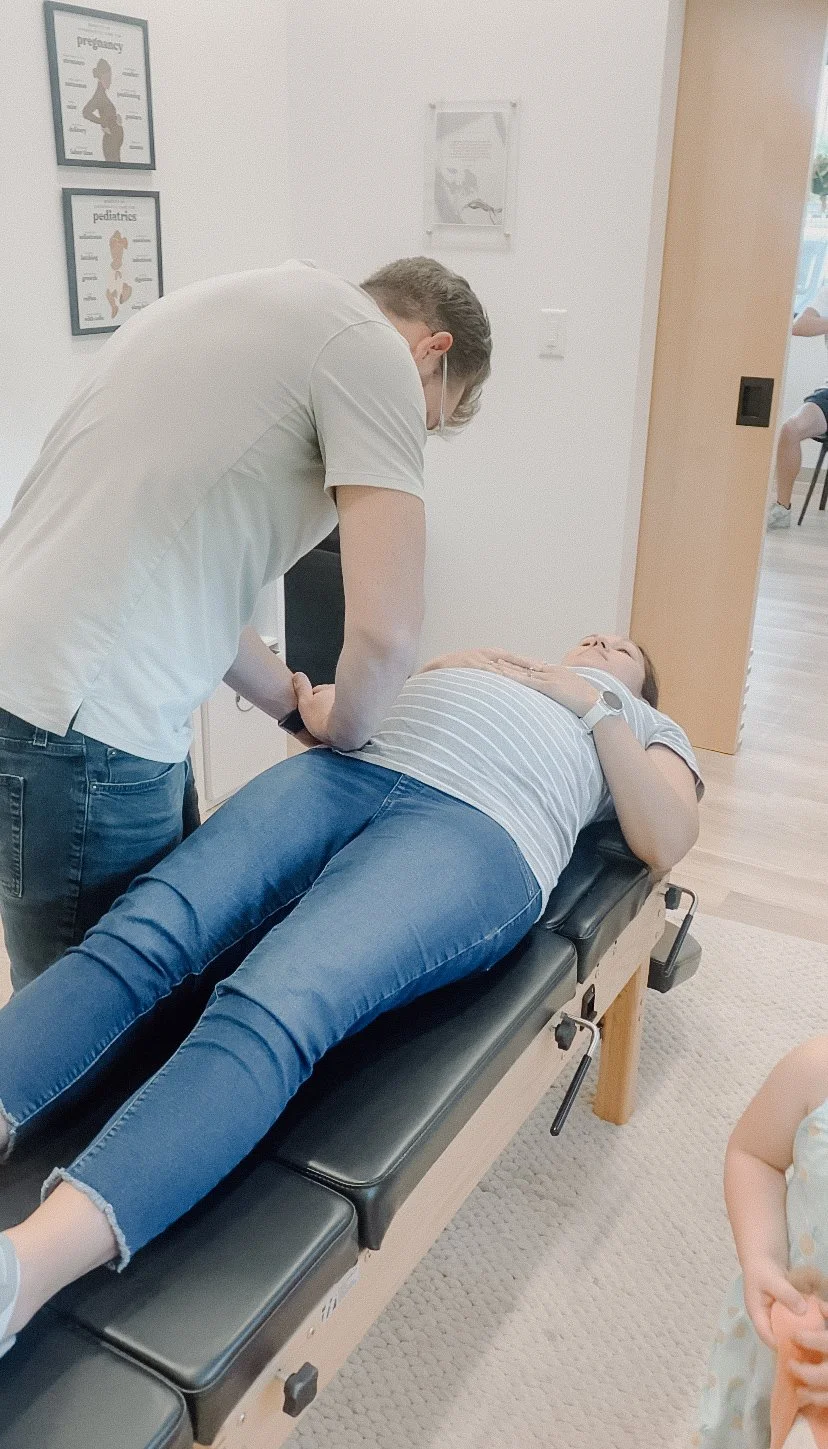 Chiropractor adjusting a woman's lower back on a treatment table in a medical clinic.