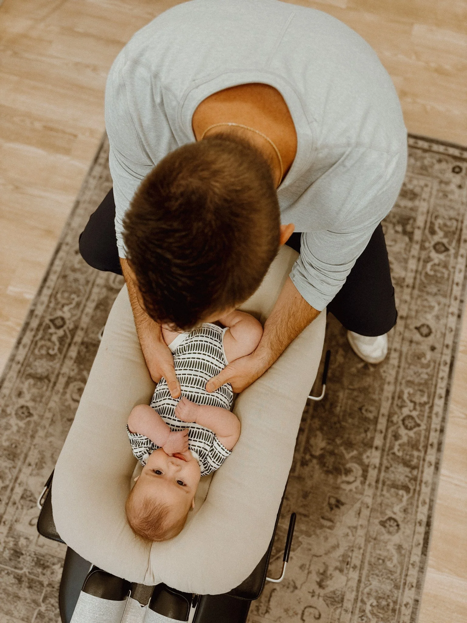 A person providing a chiropractic or massage therapy to a baby lying on a treatment table.