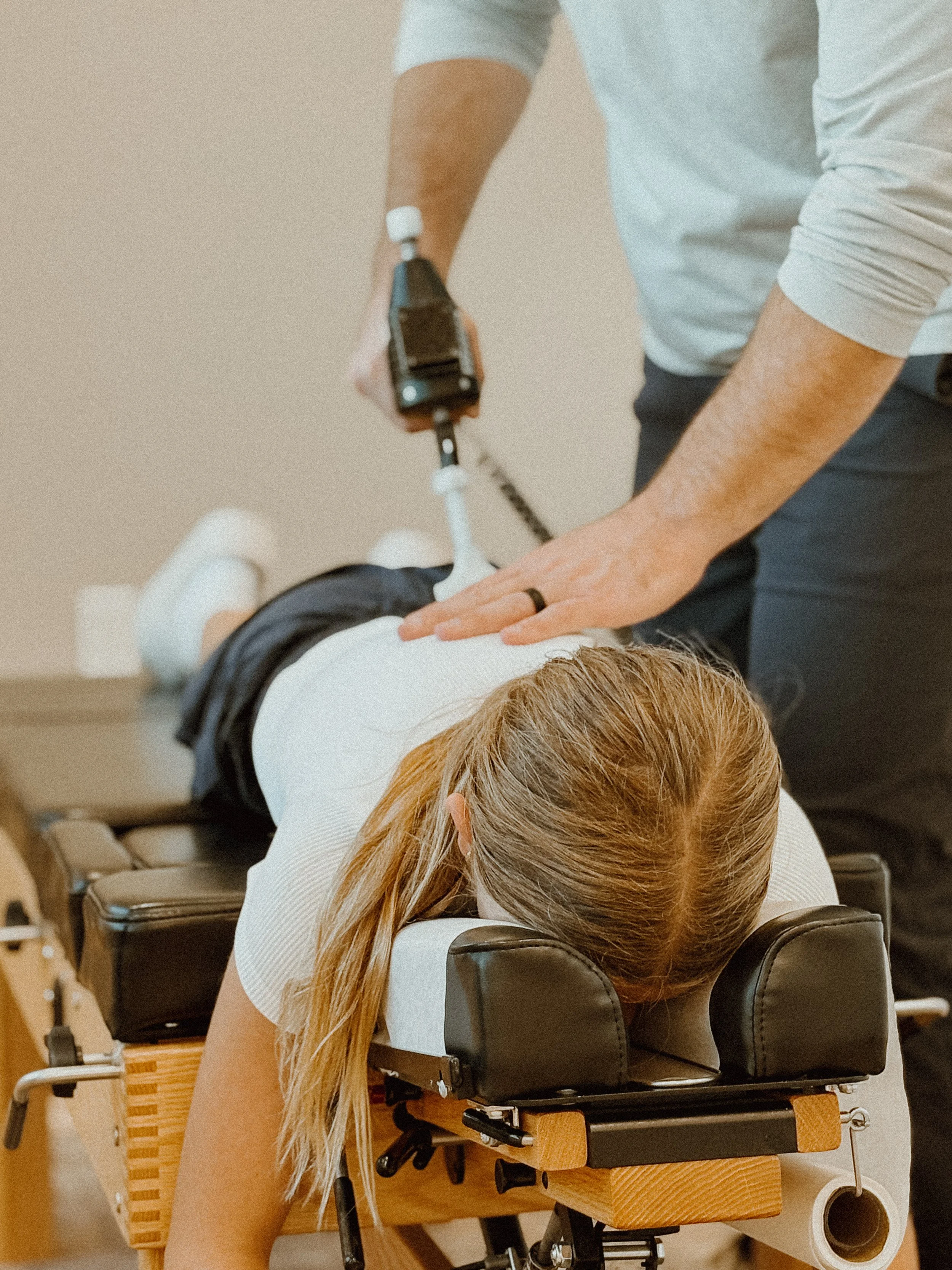 Person receiving spinal treatment from a healthcare professional in a clinical setting.