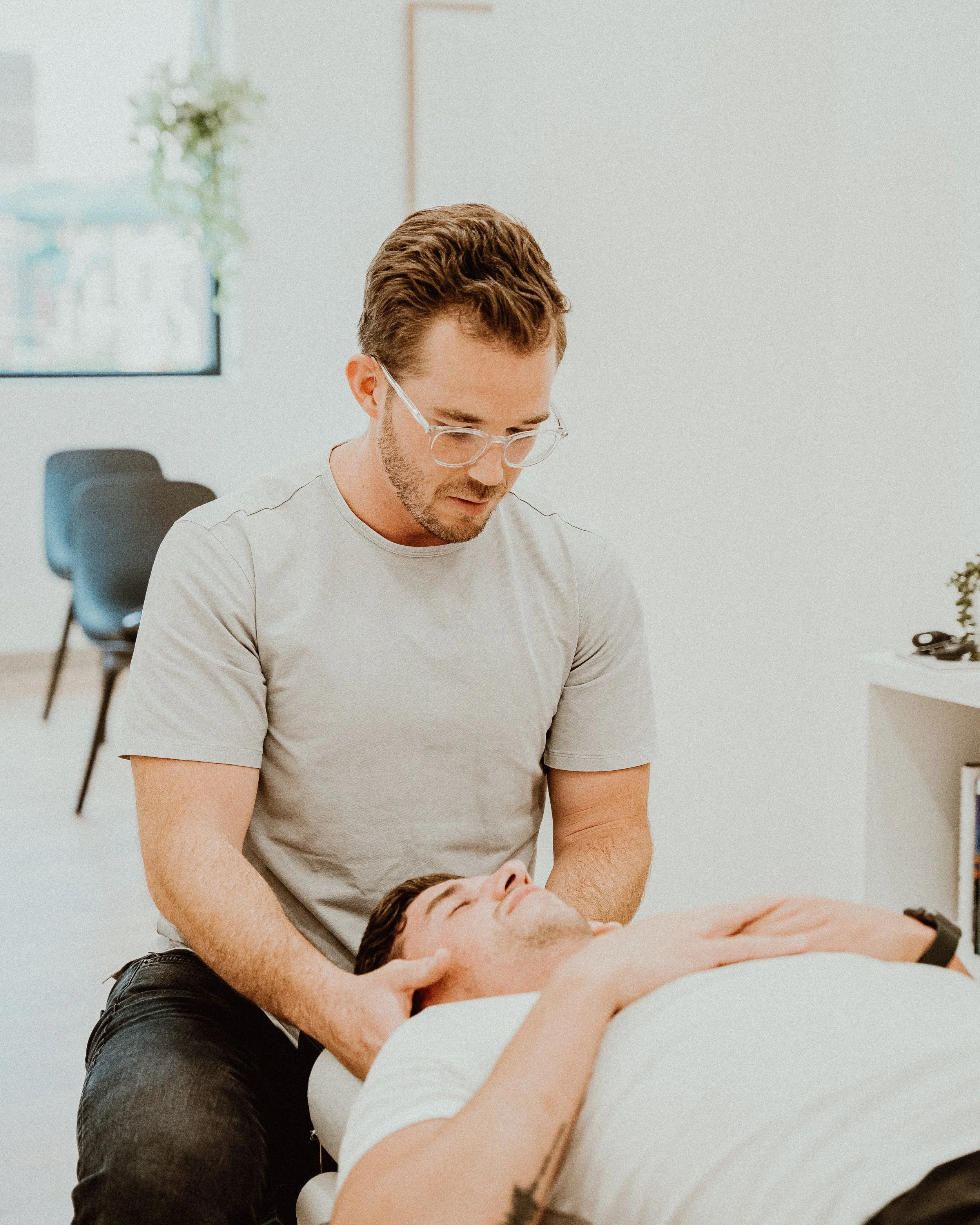 Chiropractor adjusting a patient's neck in an office setting.