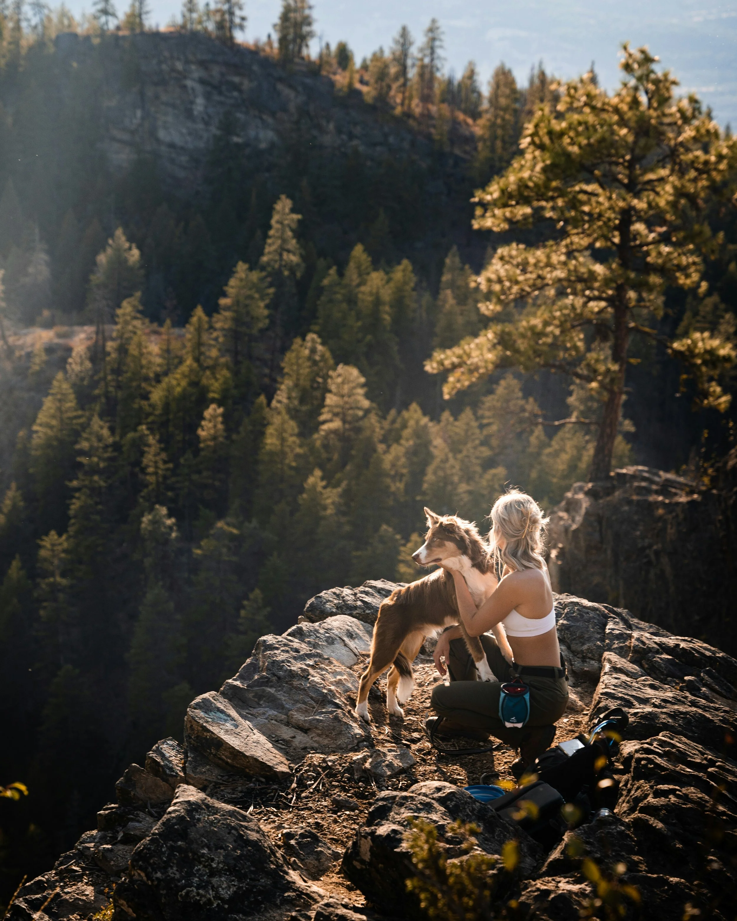 A woman with her dog on top of the mountain