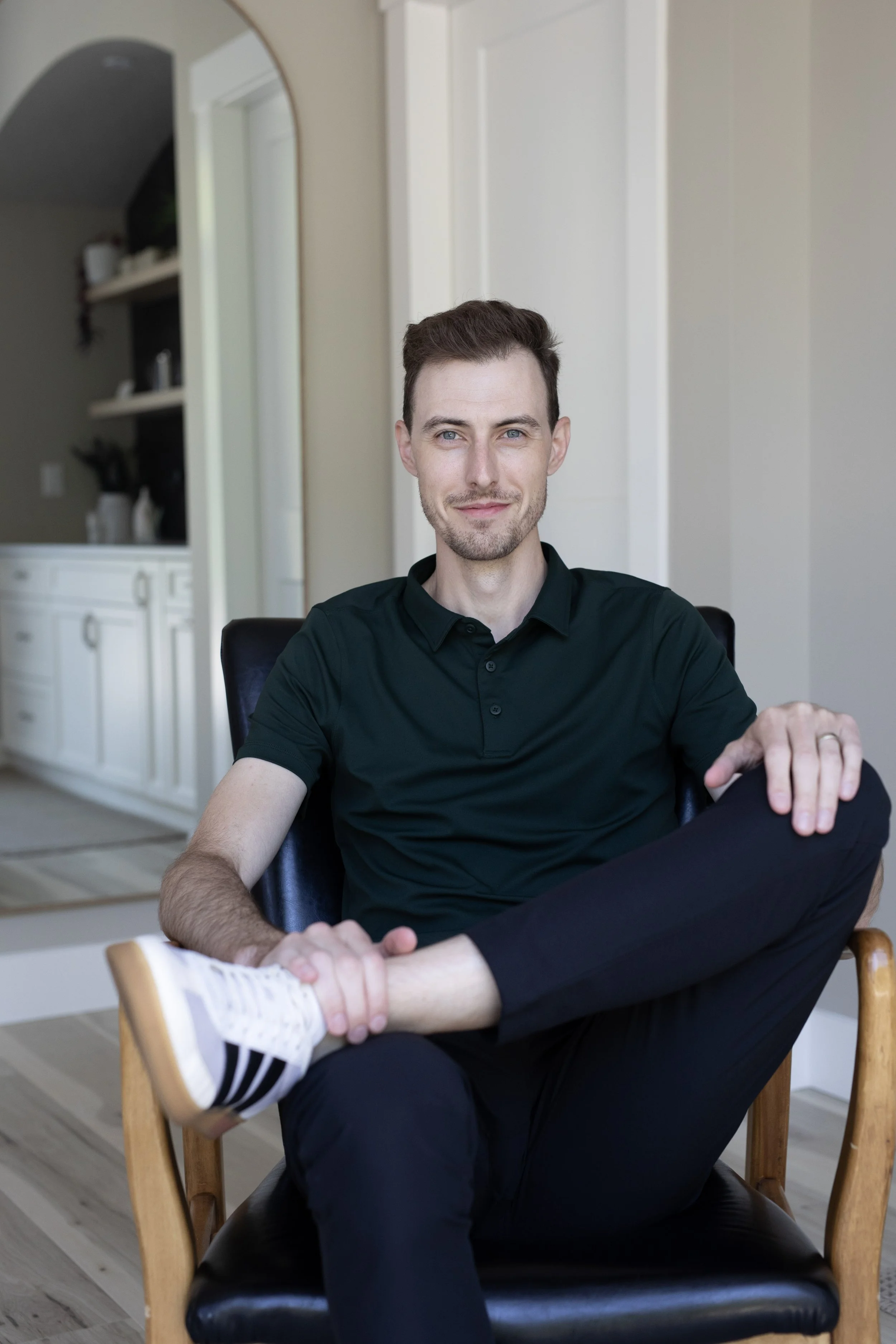 Dr. Drew Gibson, chiropractor, and co-founder of Anchor Health Co., sitting with one leg crossed over the other knee.