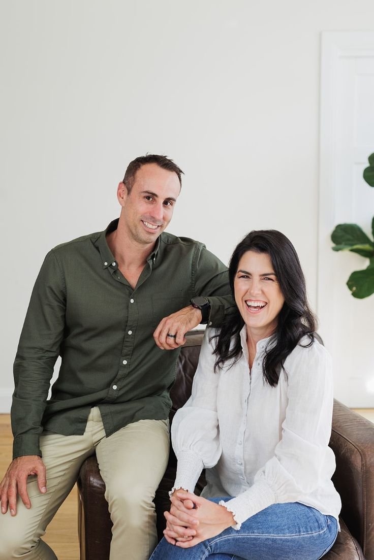 A man and a woman sitting on a couch smiling