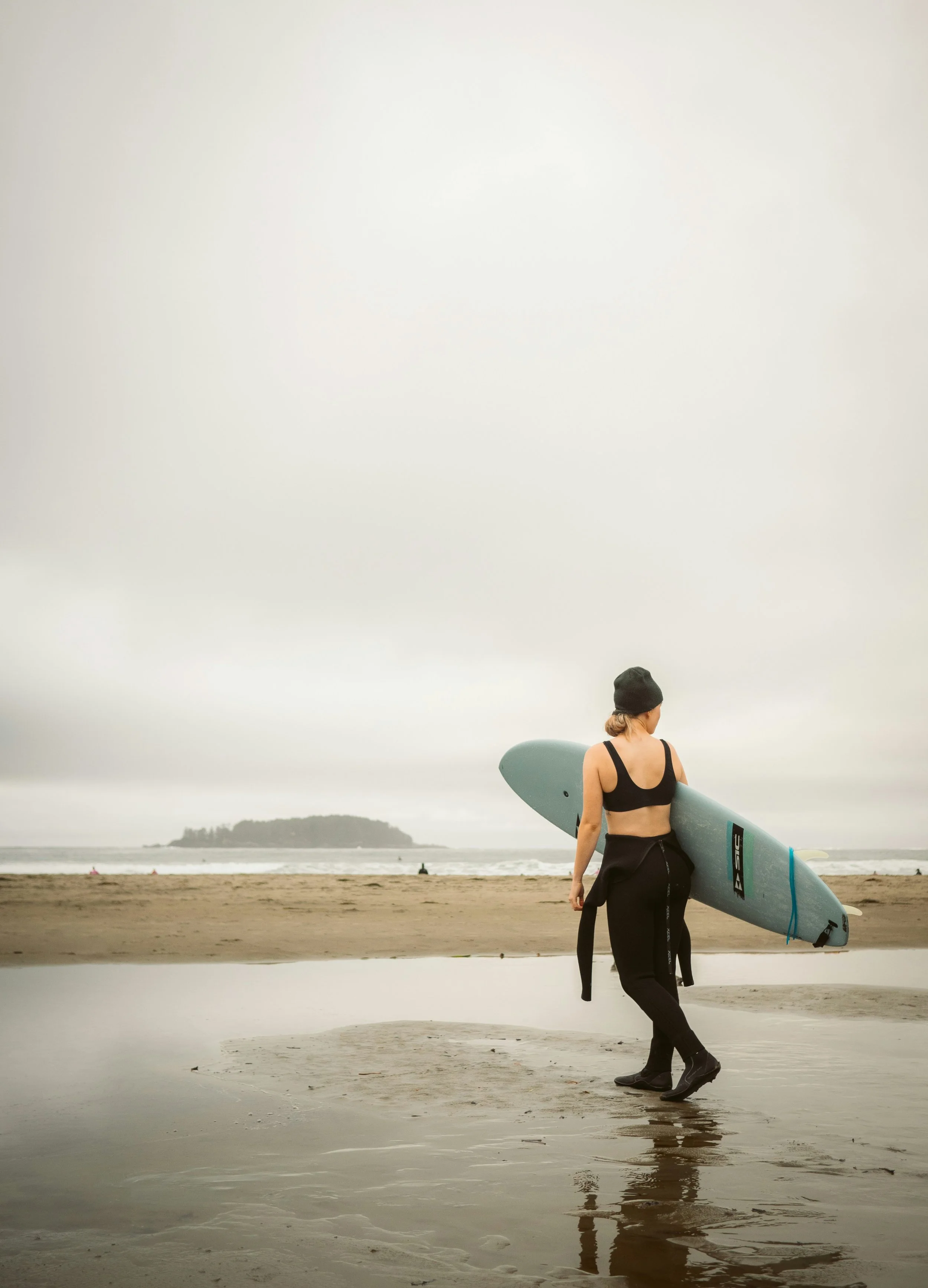 A woman walking with a surfboard